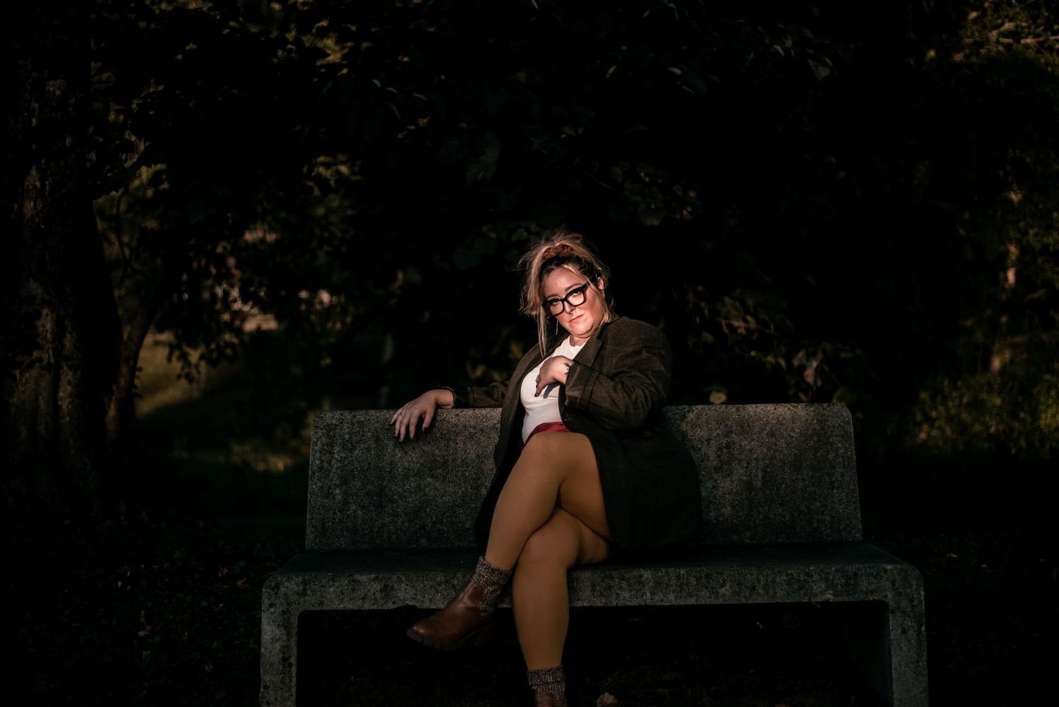 Dramatic evening photoshoot on a bench with artistic lighting and shadows.