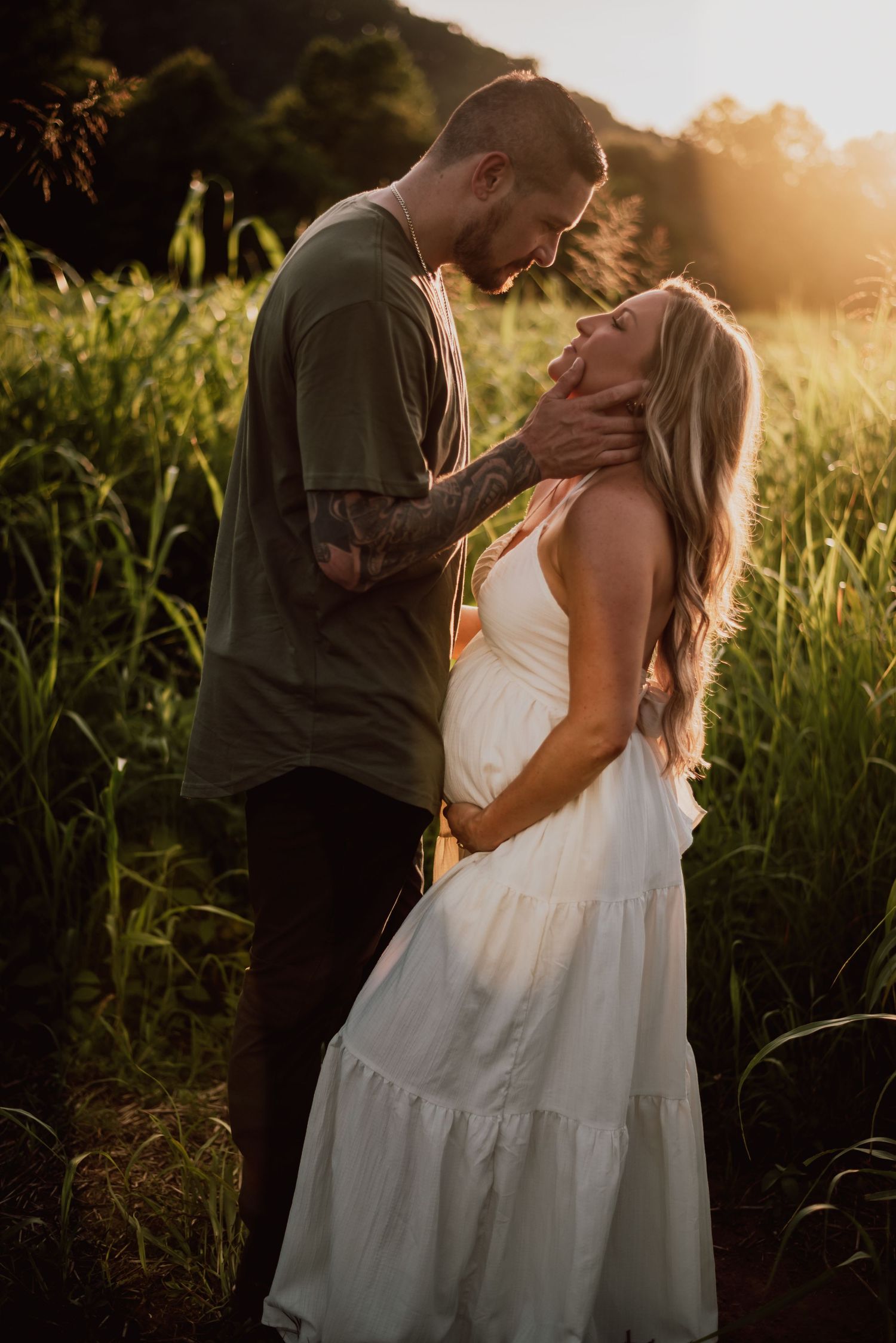 Romantic couple embracing in a sunlit field during golden hour.