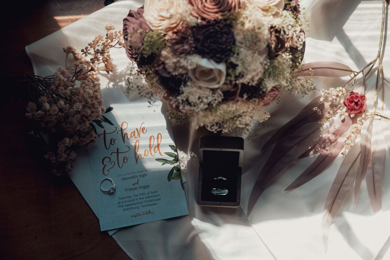Wedding stationery and floral arrangements artistically arranged in soft natural lighting.