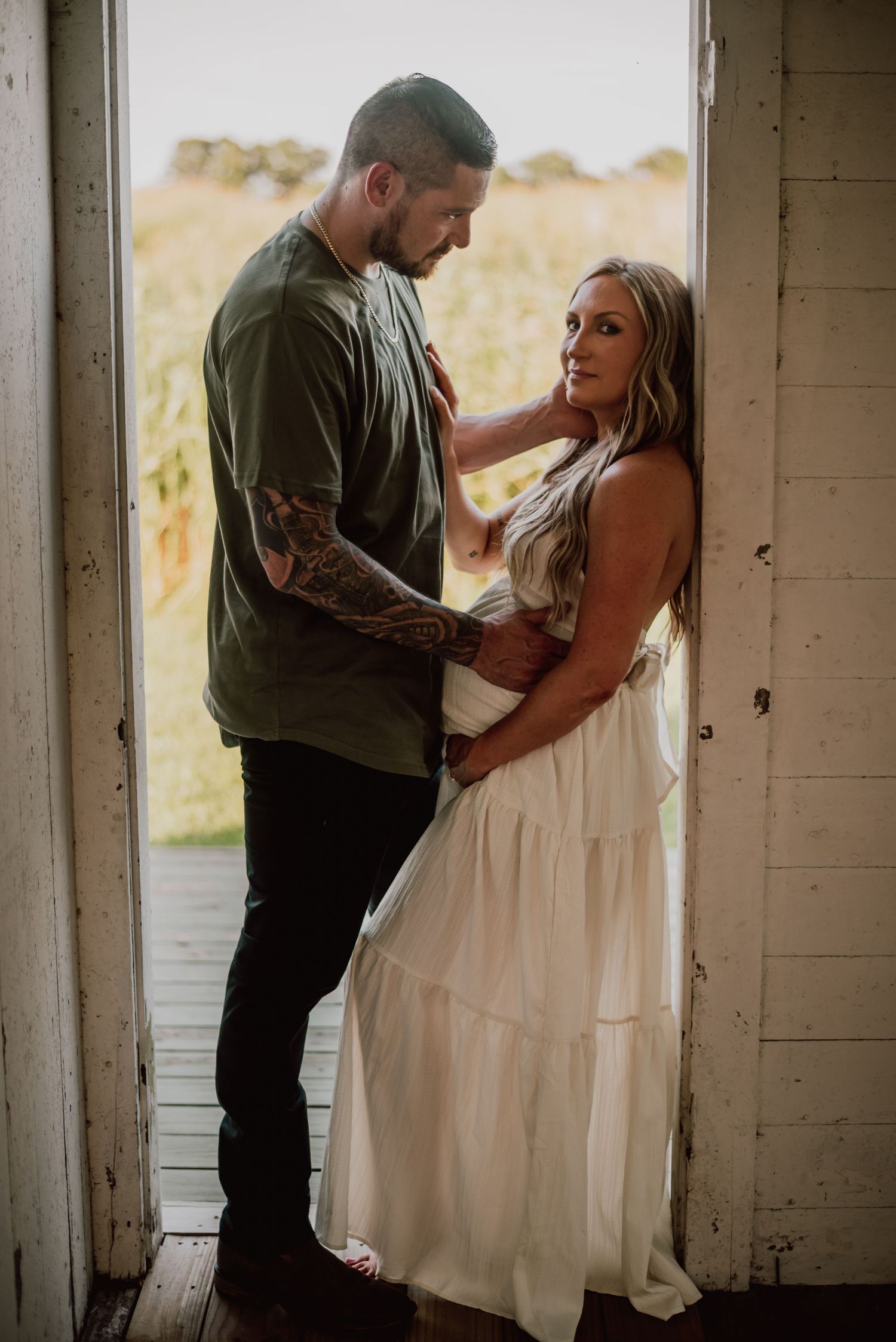 Intimate maternity photo of a couple embracing on a rustic white porch.