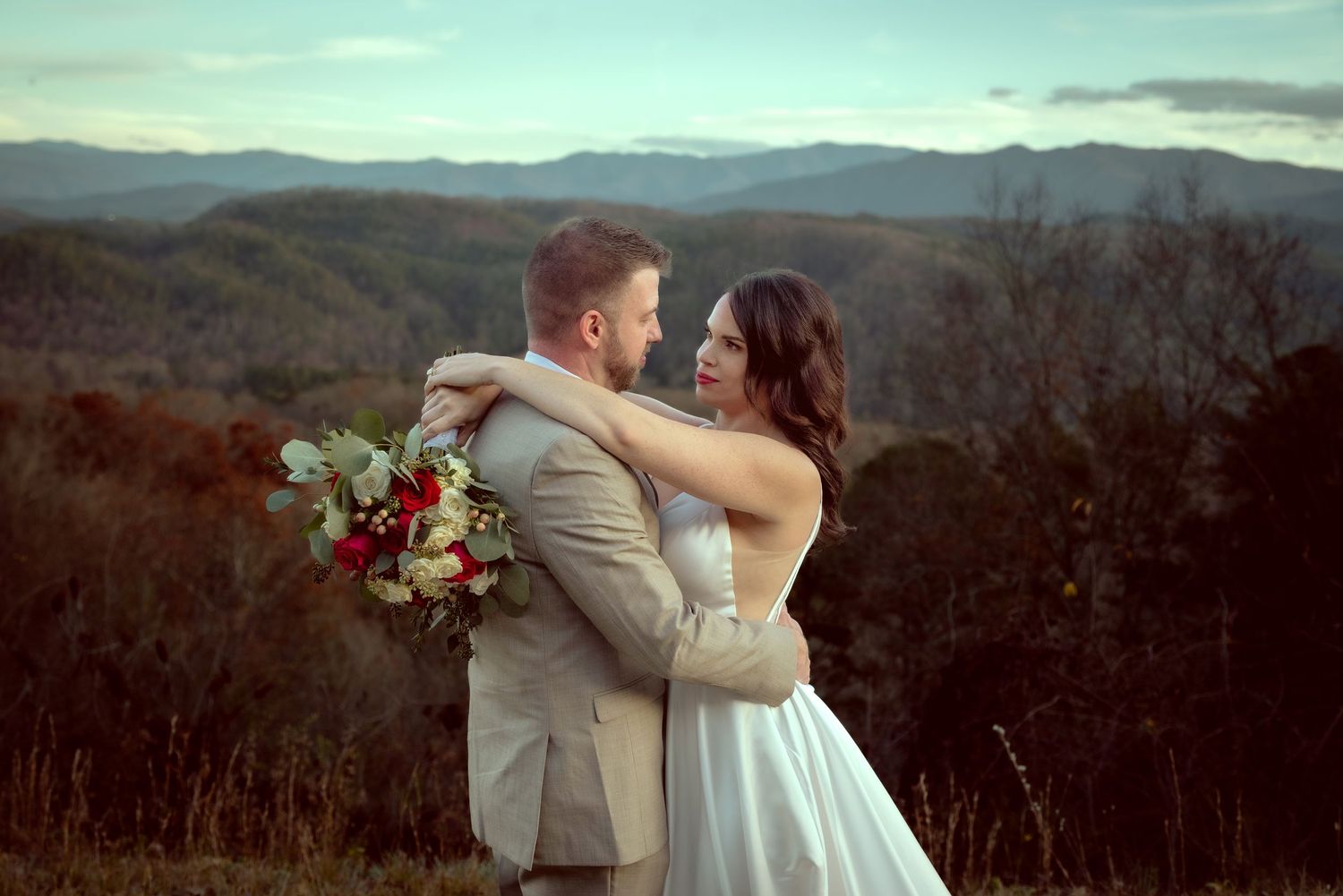 Scenic mountain landscape at sunset with a couple embracing in silhouette against the dramatic sky.