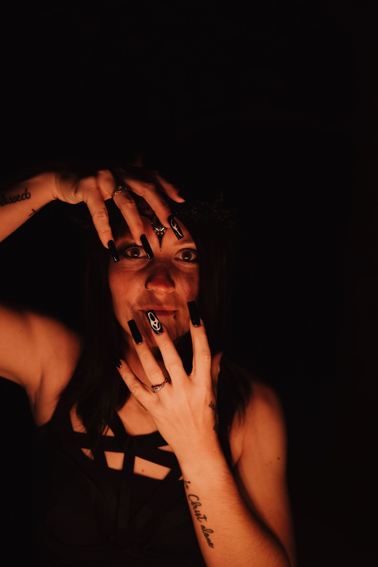 Artistic portrait with hands framing face in dramatic red lighting.