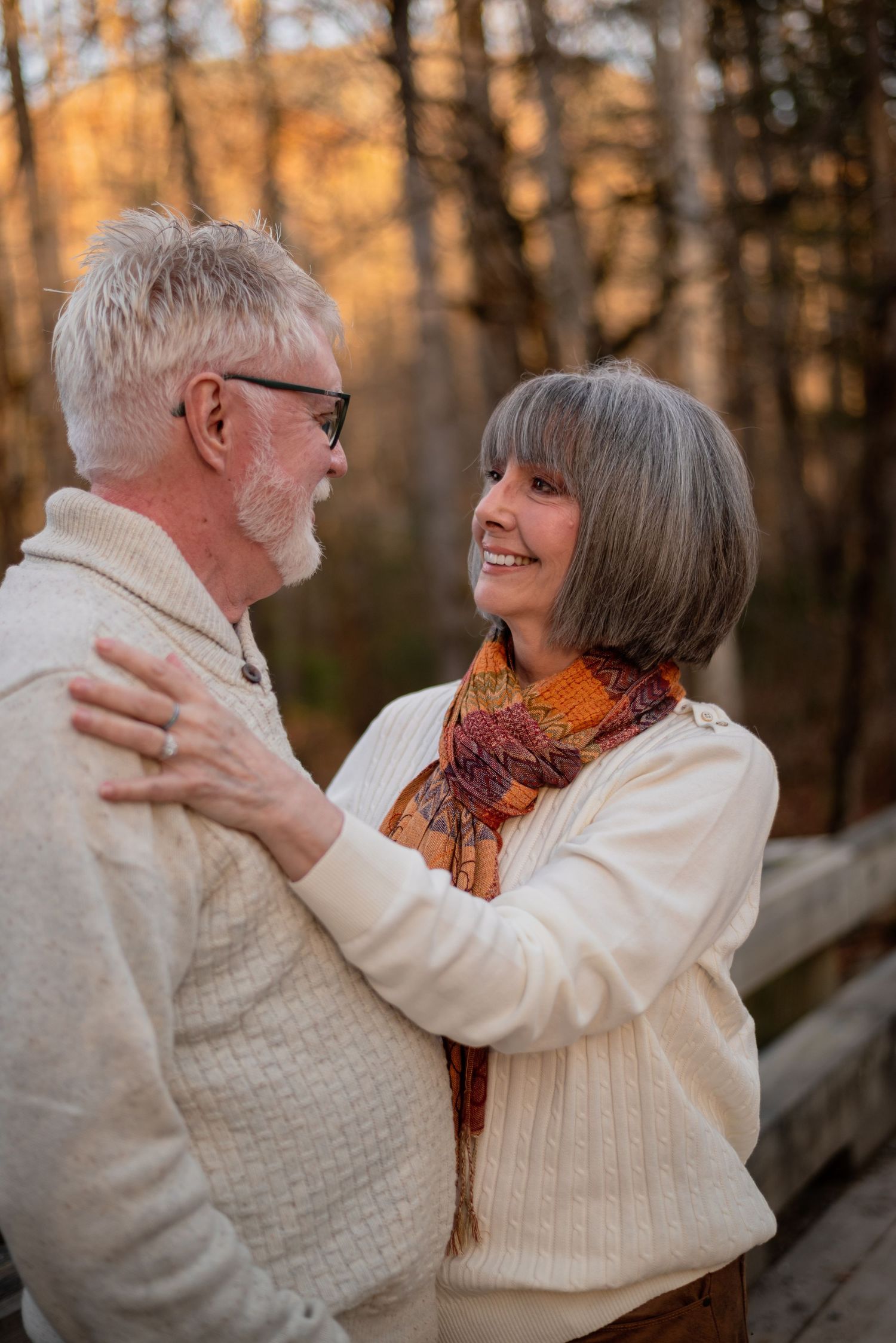 Senior couple embracing and dancing together in a wooded area during sunset.