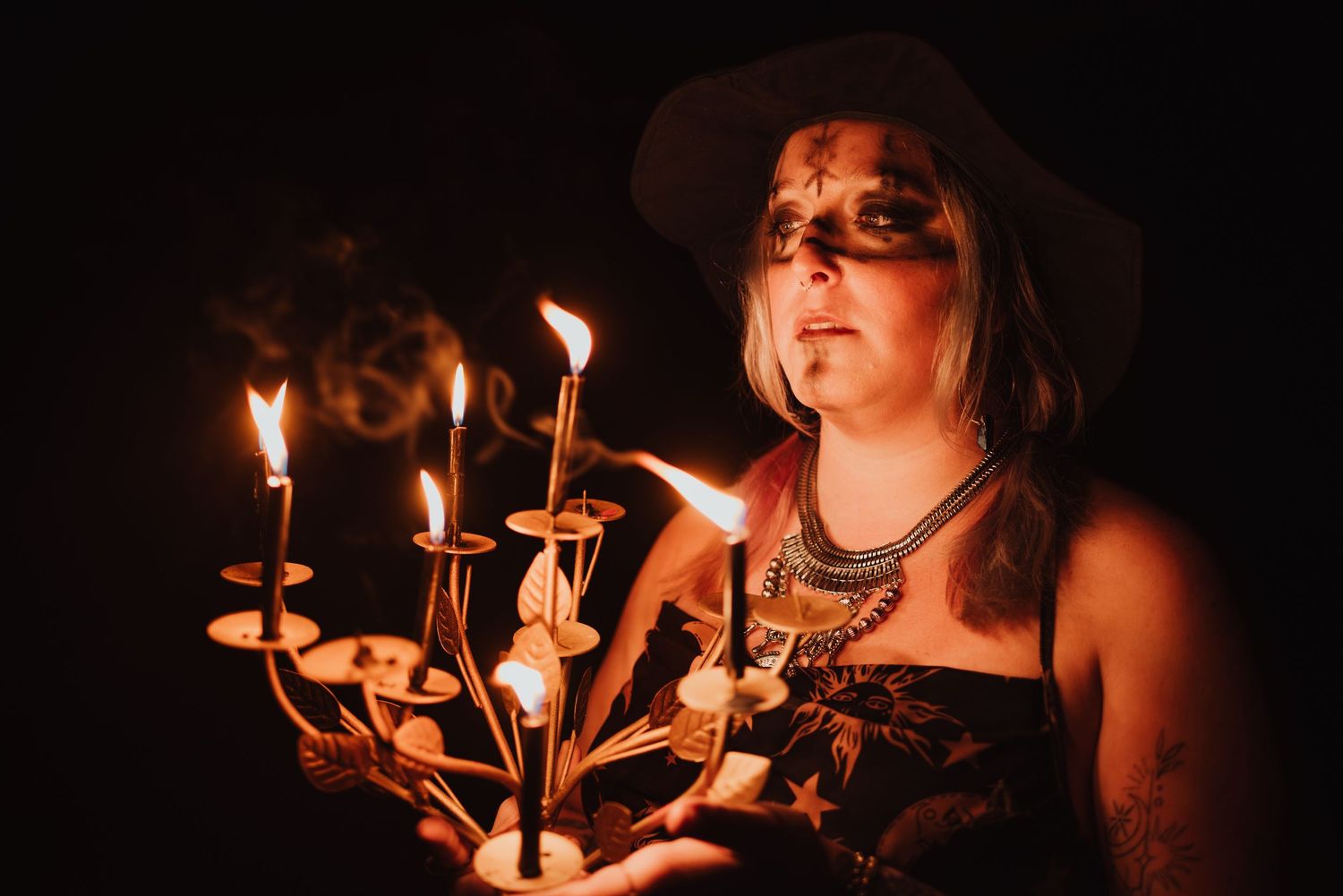 Dark atmospheric photo of someone holding a glowing candelabra while wearing gothic attire.