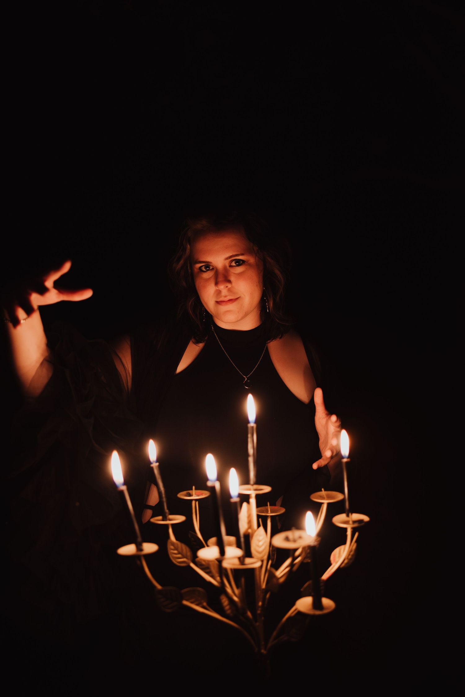 Atmospheric portrait illuminated by multiple candles on an ornate candelabra against a dark background.