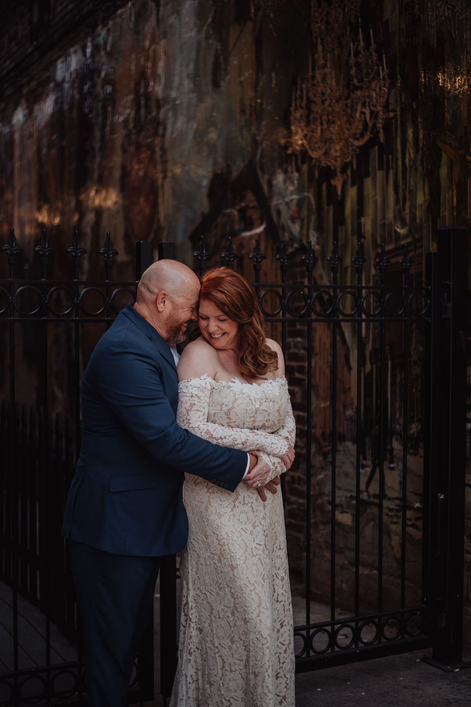 Couple sharing intimate moment against rustic iron gate backdrop.