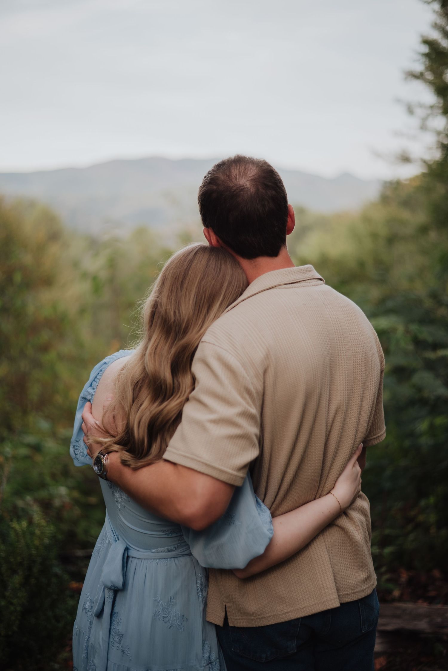 Couple embracing while looking at mountain vista during sunset.