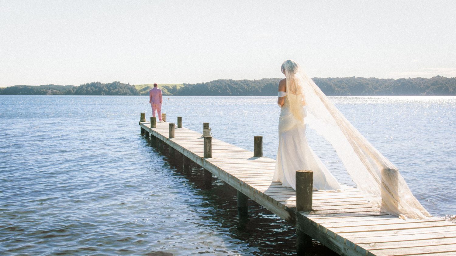 A sequence of photos showing a wedding dress flowing in the wind on a lakeside dock during a sunny day.