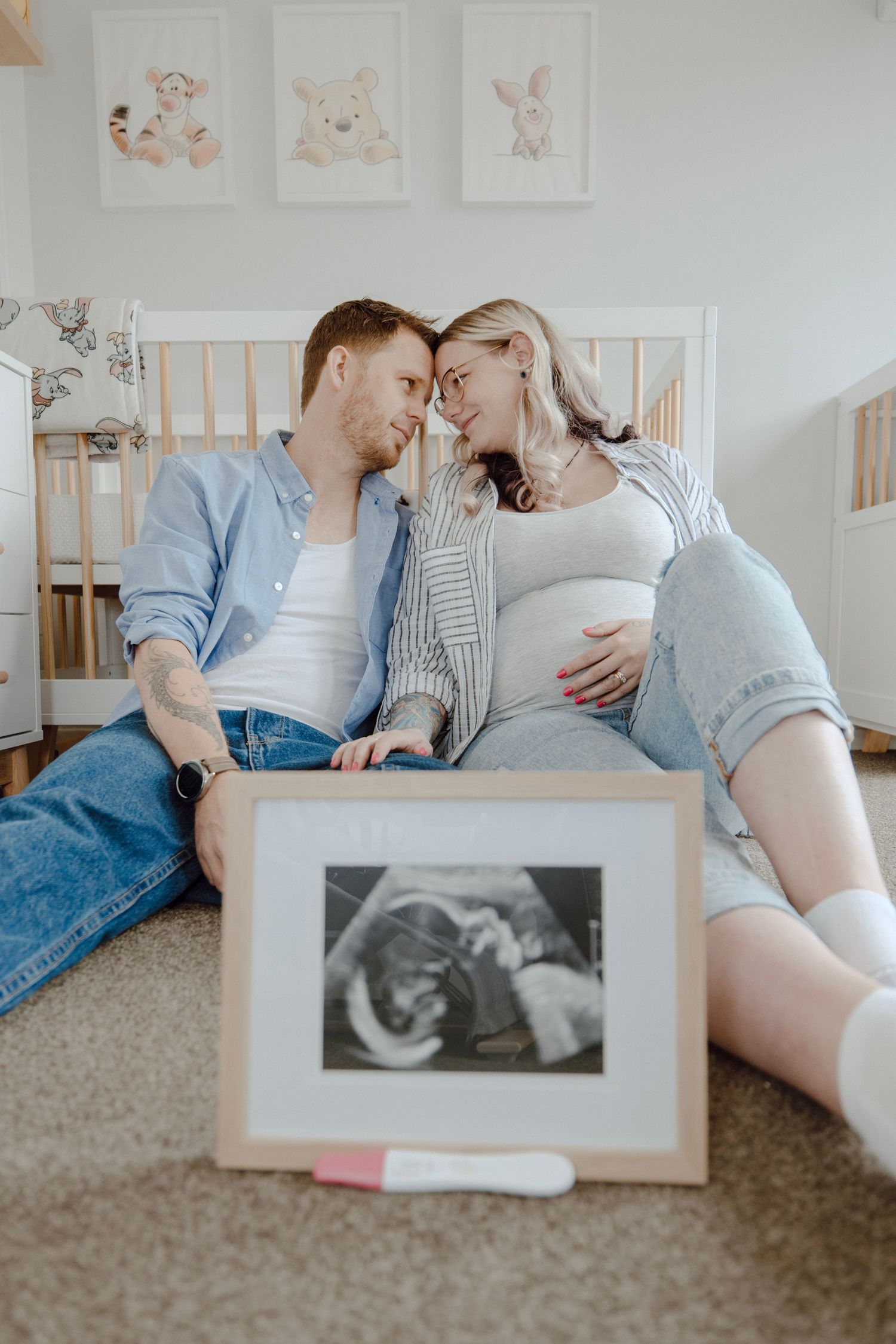 A couple lies on carpet looking at ultrasound photos in a series of intimate pregnancy announcement moments.