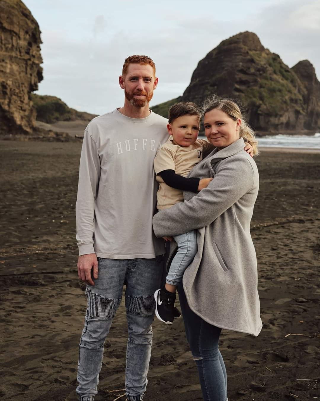 Family enjoying time together on a moody beach with dramatic coastal cliffs.