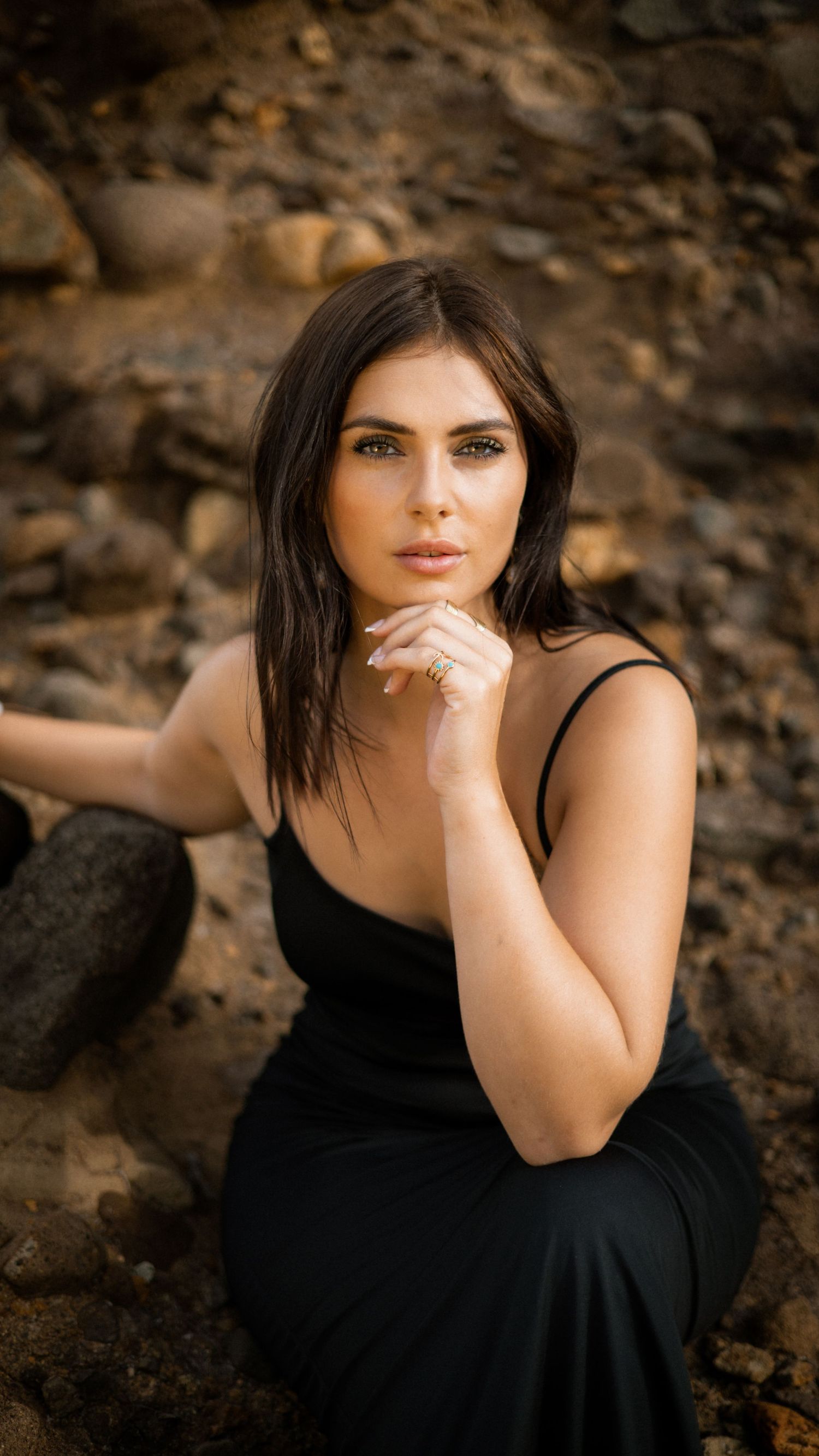 Intimate portrait against natural stone backdrop with warm lighting.