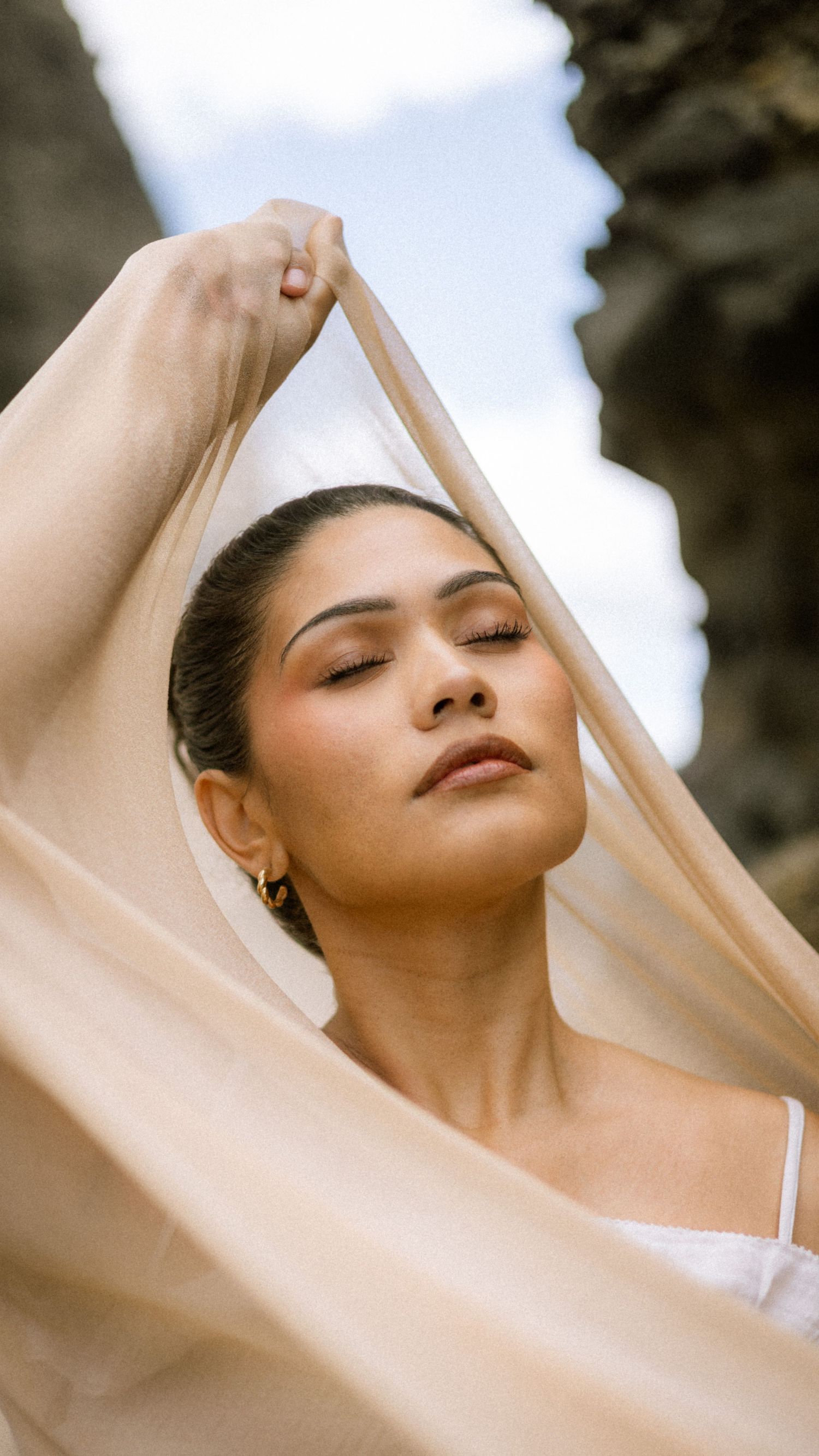A series of artistic portraits showing a person with closed eyes and flowing beige fabric creating an ethereal mood.