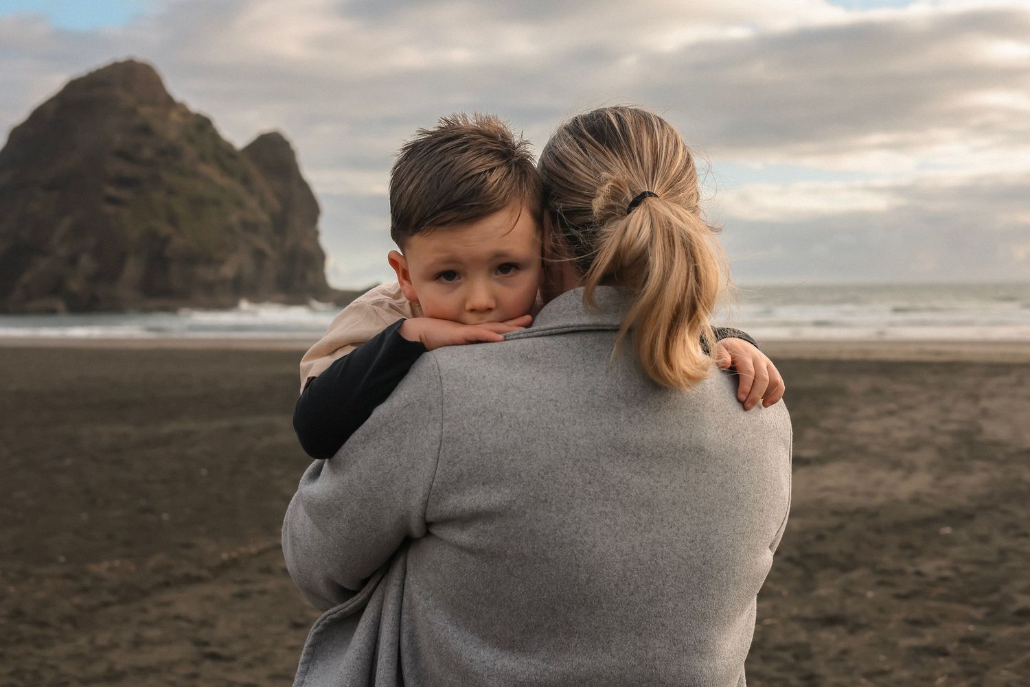 Tender embraces shared between family members on a cloudy beach at sunset.