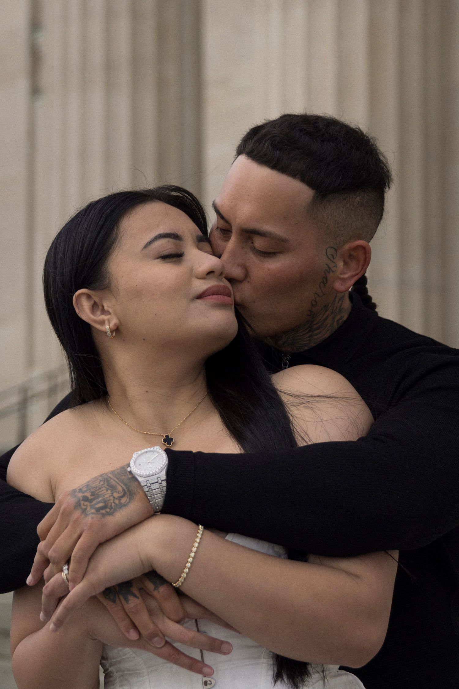 Romantic embrace captured against backdrop of classical stone columns.