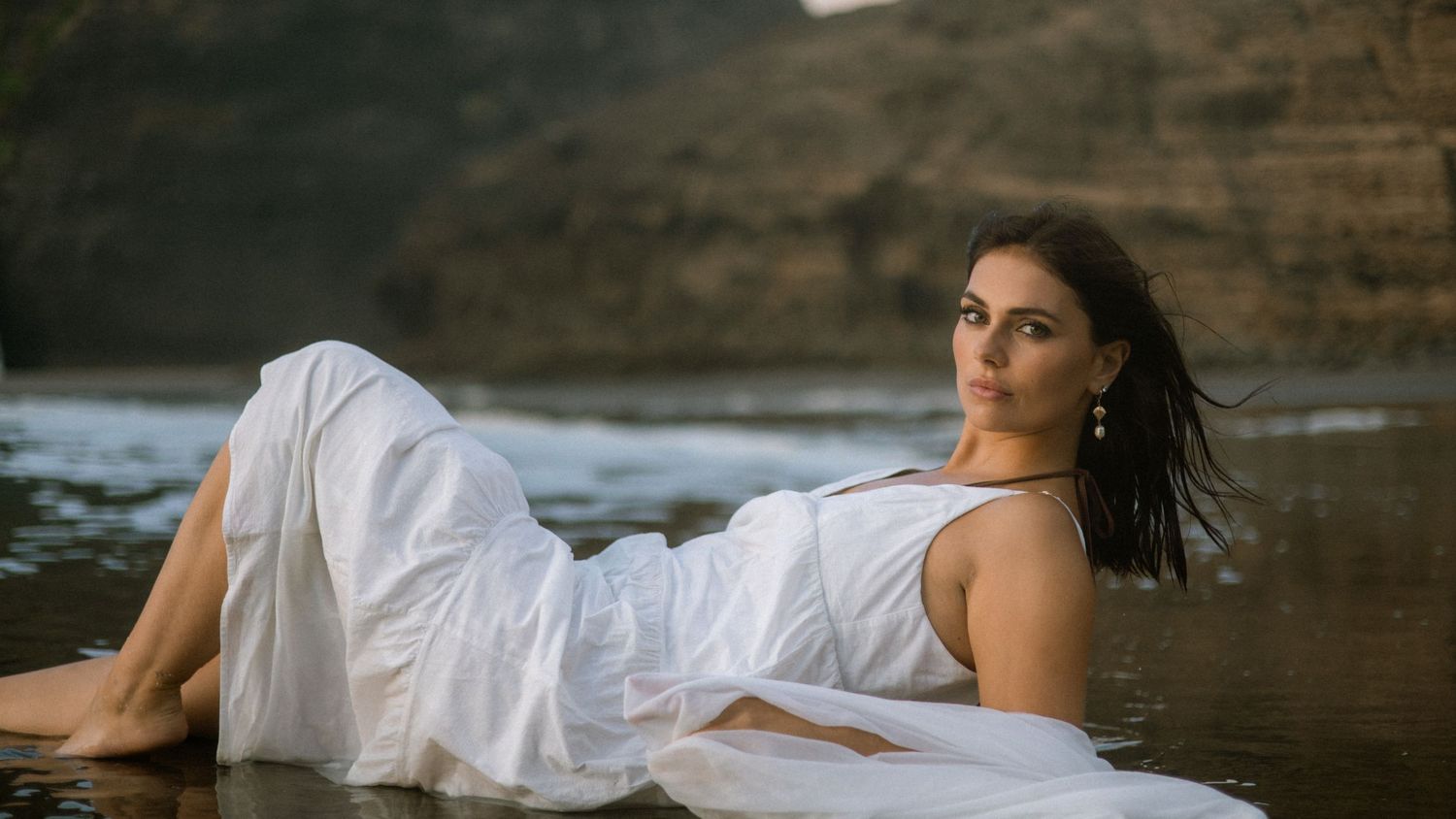 Artistic beach portrait series with flowing fabric and dramatic coastal backdrop.