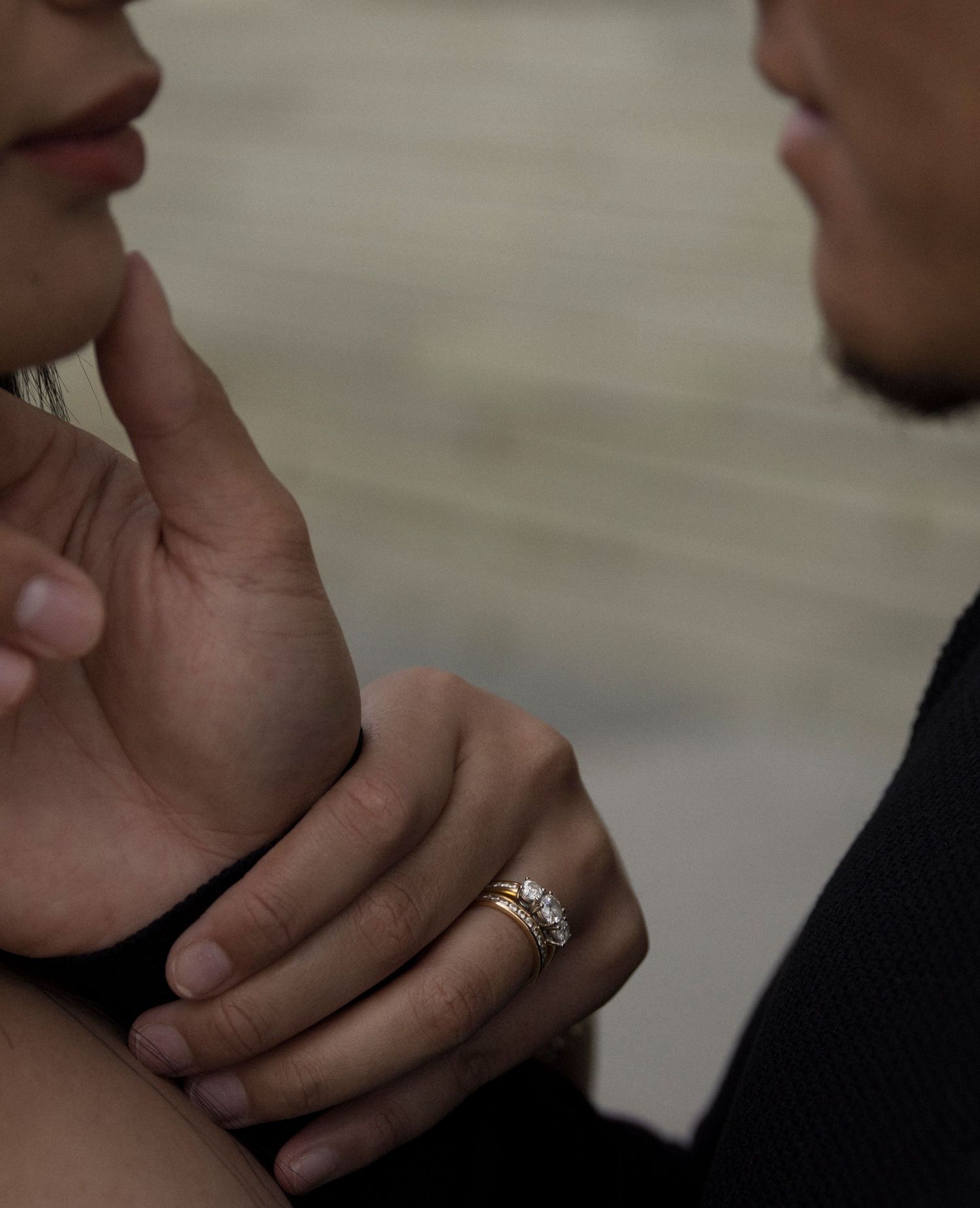 Close up shot of hands with a sparkling engagement ring in soft lighting.