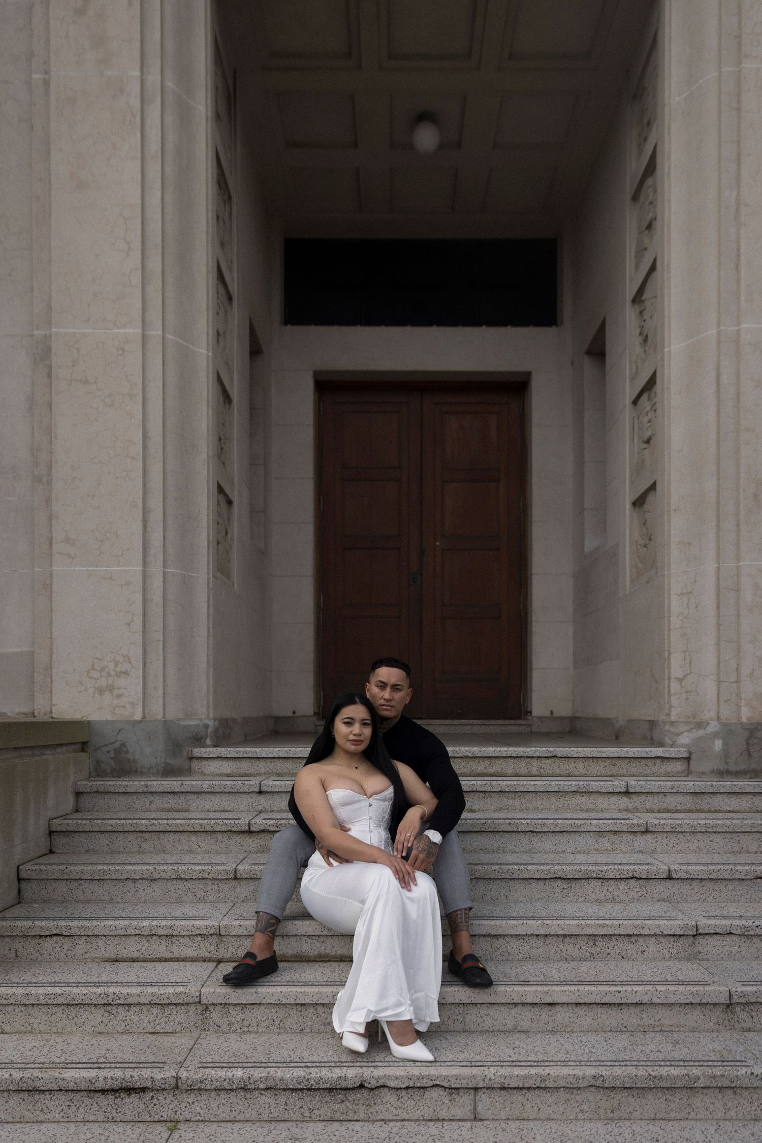Couple relaxing on wide stone steps of a historic building.