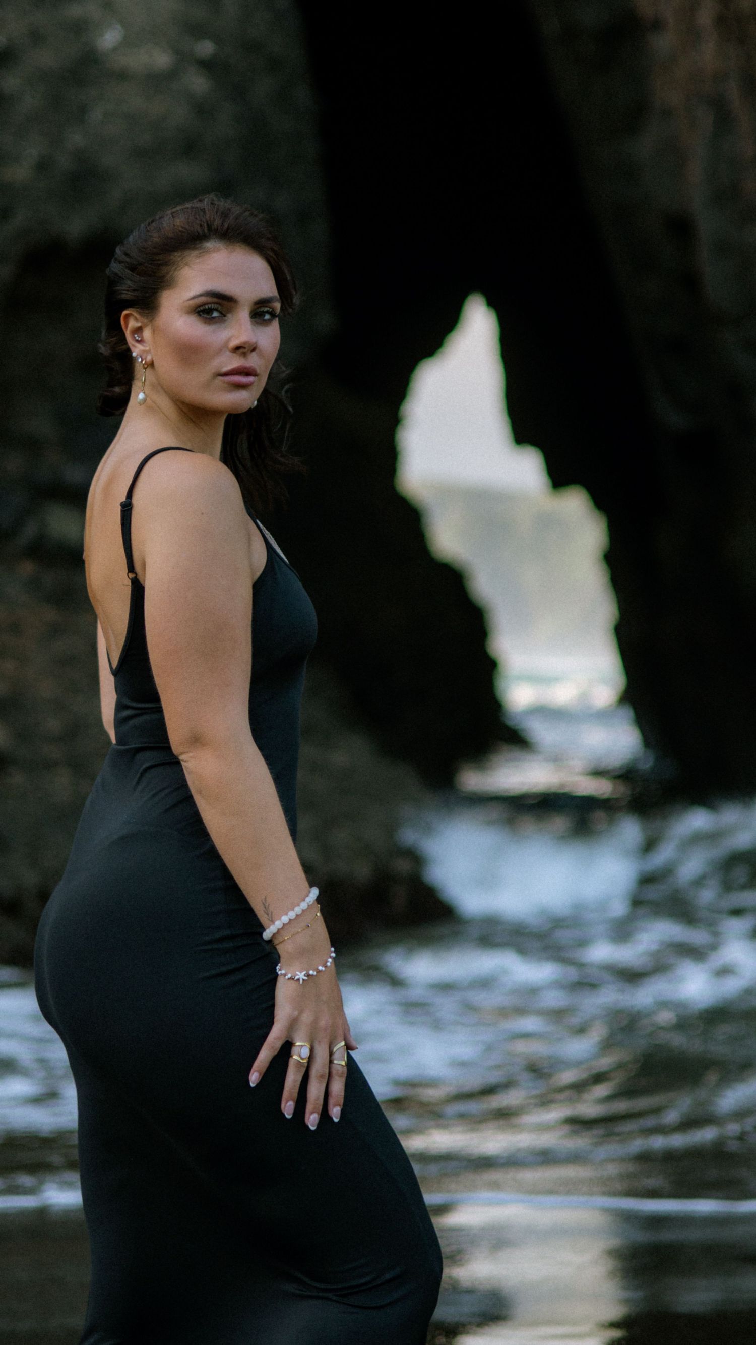 Dramatic silhouette against coastal rocks and water during sunset photoshoot.