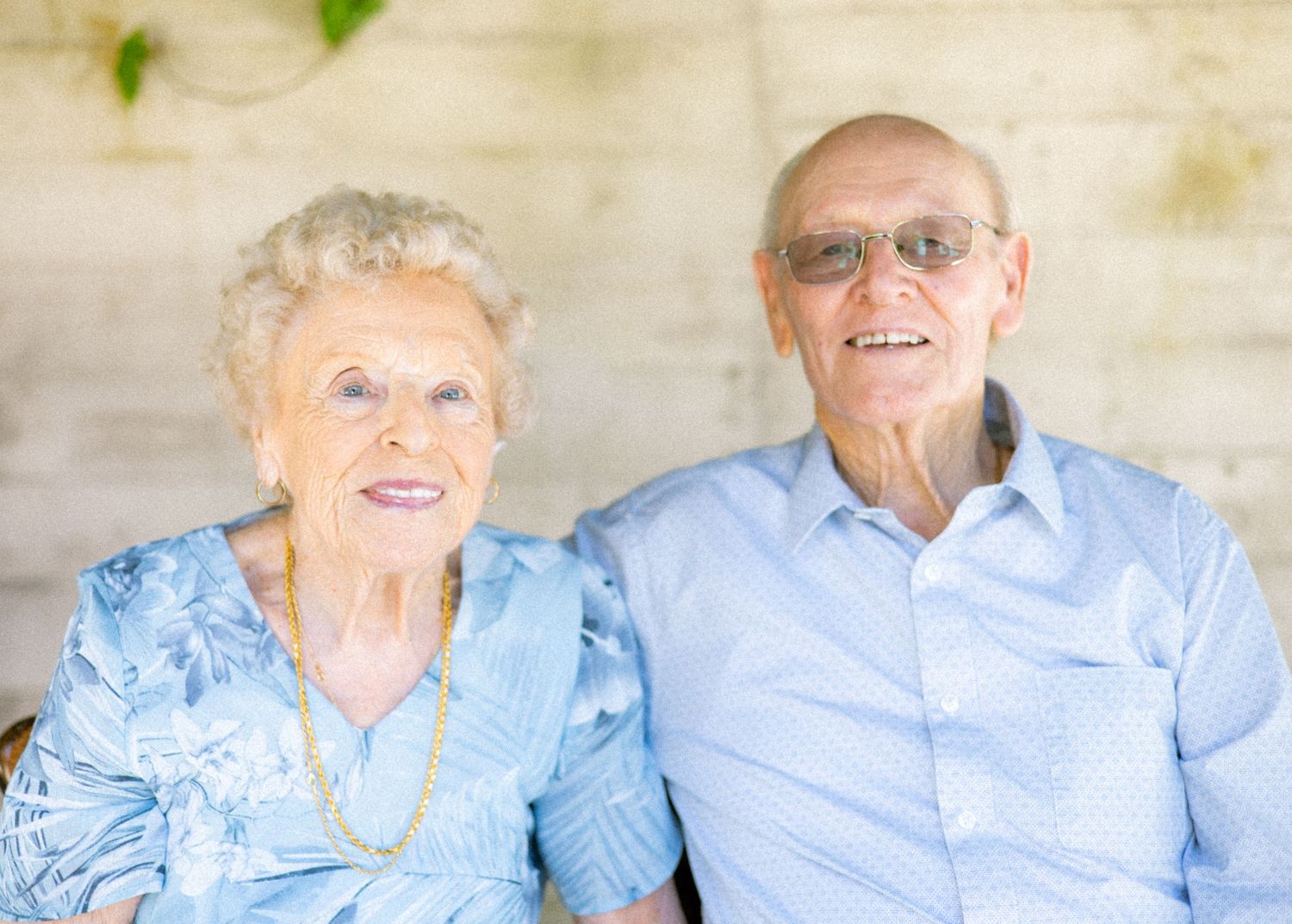 Elderly couple sitting together and sharing joyful moments in matching light blue outfits.