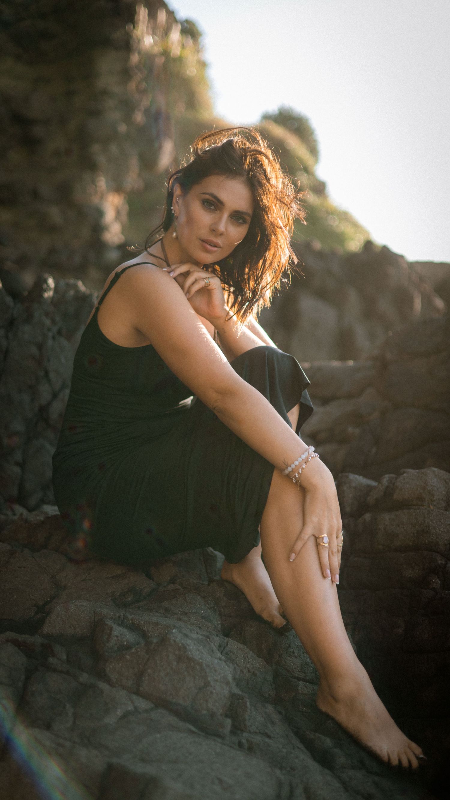 Sunset portrait session among coastal rocks with dramatic lighting.