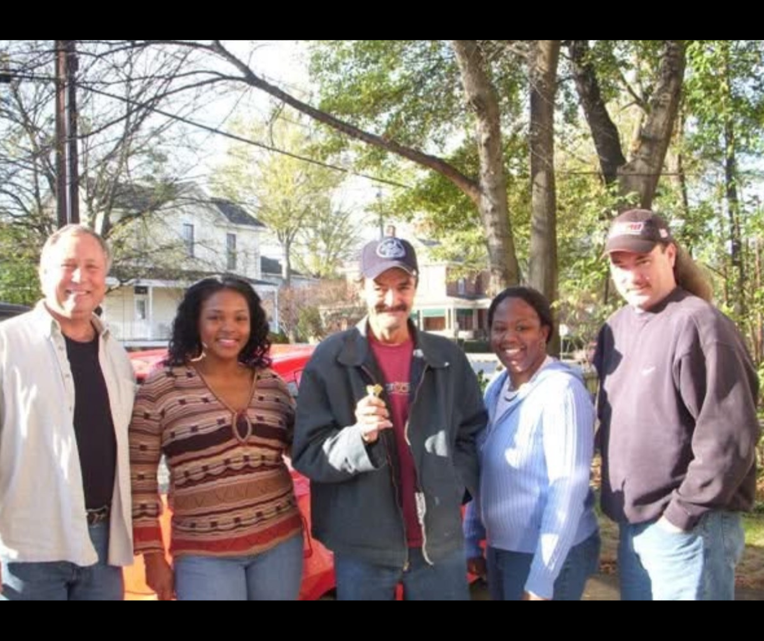 A group of people standing together outdoors. With a client who change his life from being homeless to having a home.