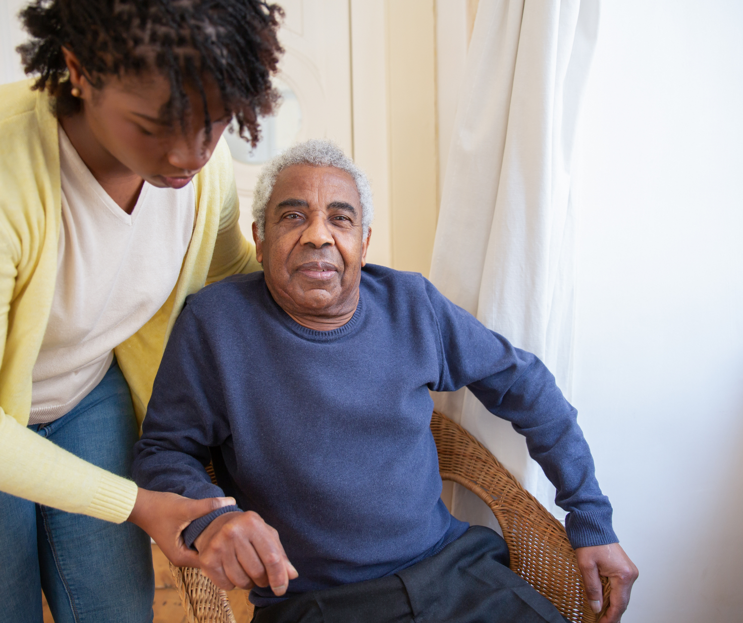 Healthcare worker assisting senior patient with physical therapy exercises in a bright home setting.