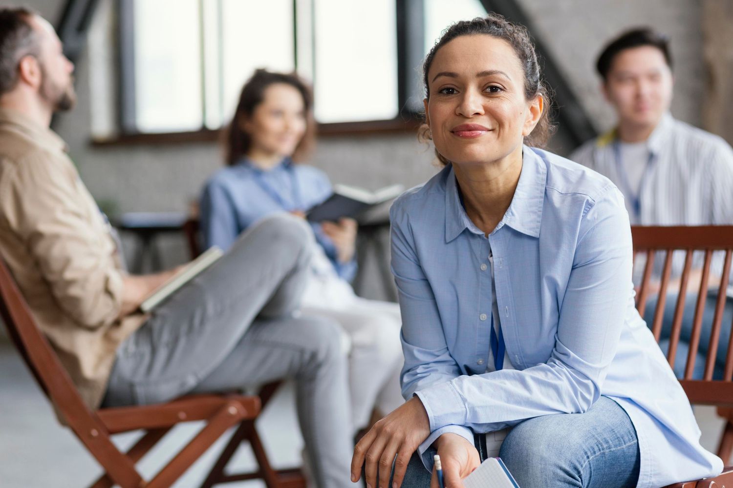 Business professionals in blue and gray attire engage in conversation during a casual office meeting.