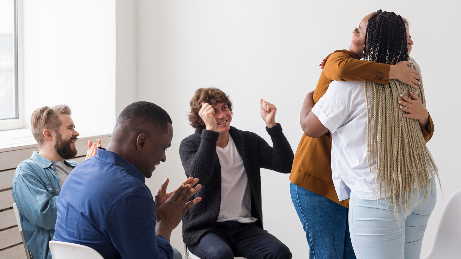 An image showing people hugging and embracing in a group session.