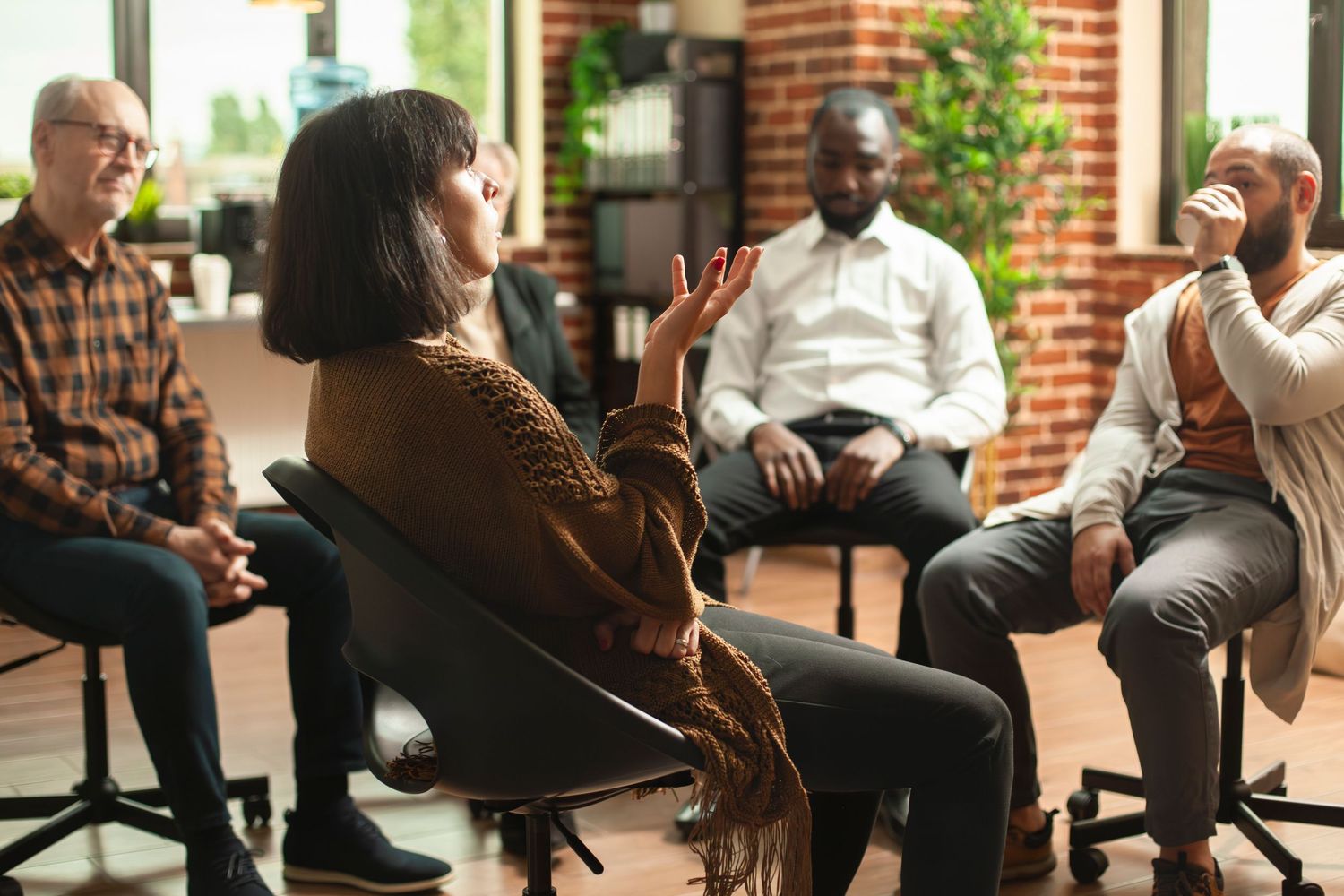 Group of clients sitting in office chairs engage in animated discussion during a casual meeting.