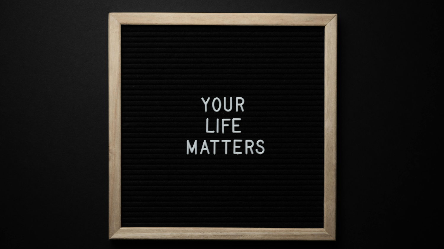 Three black letterboard signs with white text reading 'YOUR' and 'LIFE MATTERS' against dark background.