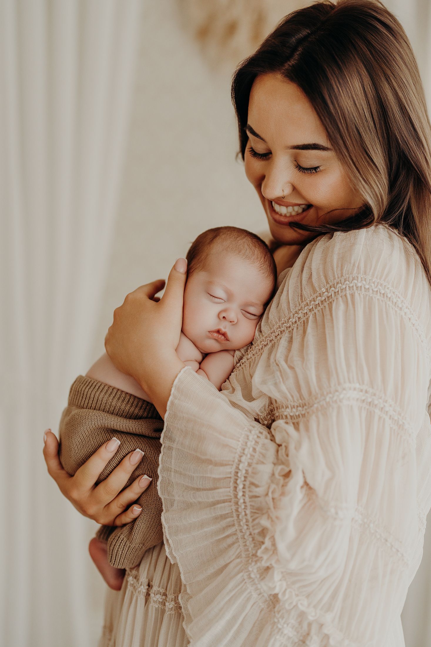 A tender moment captured in soft light as mum and newborn share intimate bonding time in a romantic maternity dress