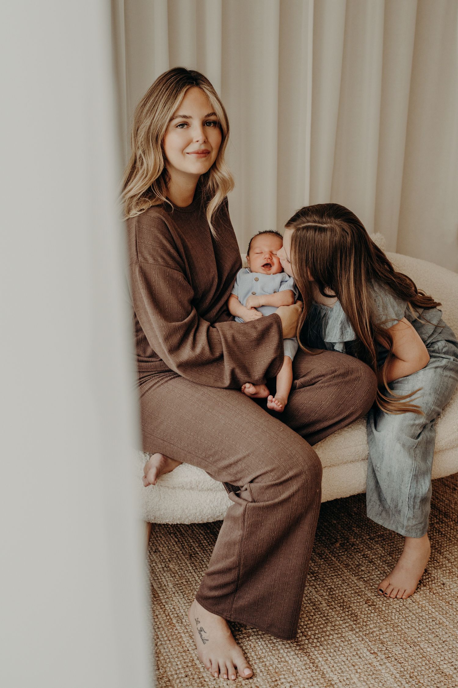 Intimate family moment on carpet showing parent bonding with newborn in brown sweater.
