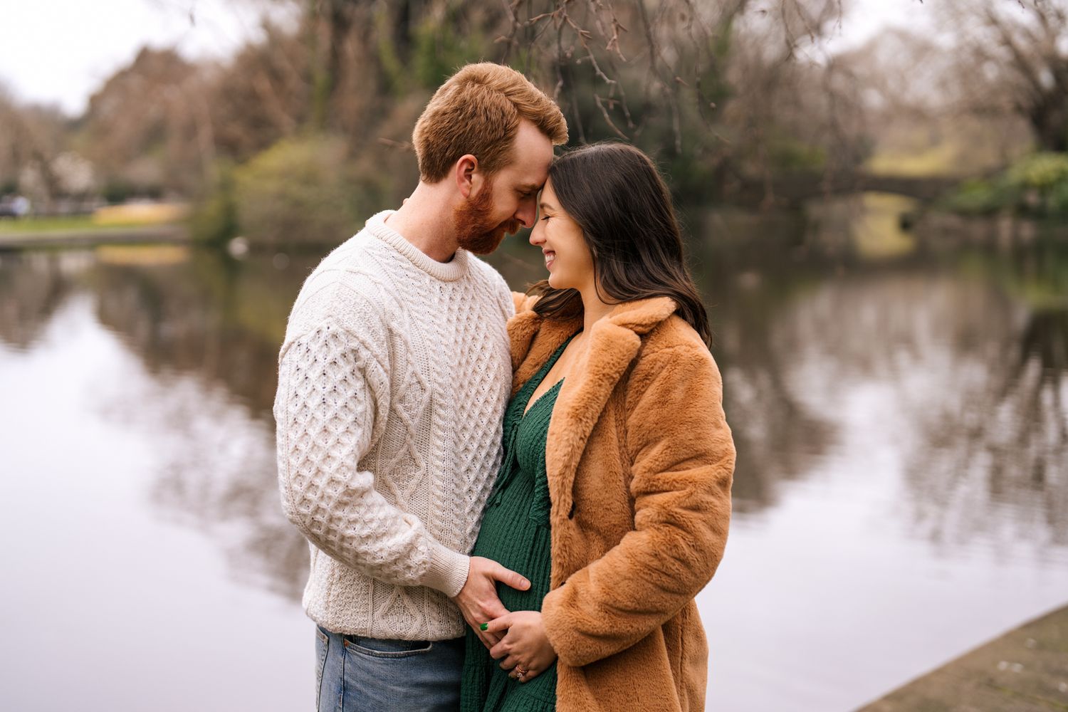 A young couple embracing in a scenic outdoor setting near a body of water.