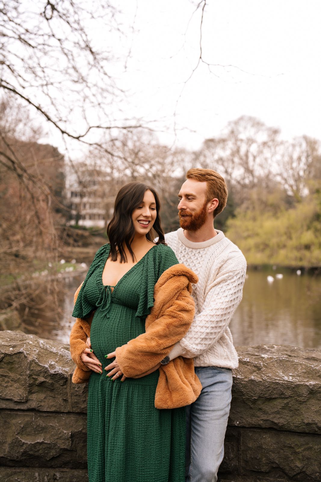 A happy couple embracing in a scenic outdoor setting with trees and a body of water in the background.
