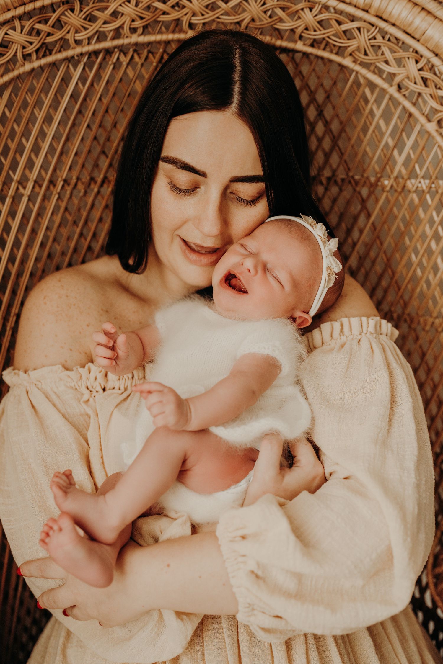 Tender moment captured in a rattan chair with white clothing and natural lighting.