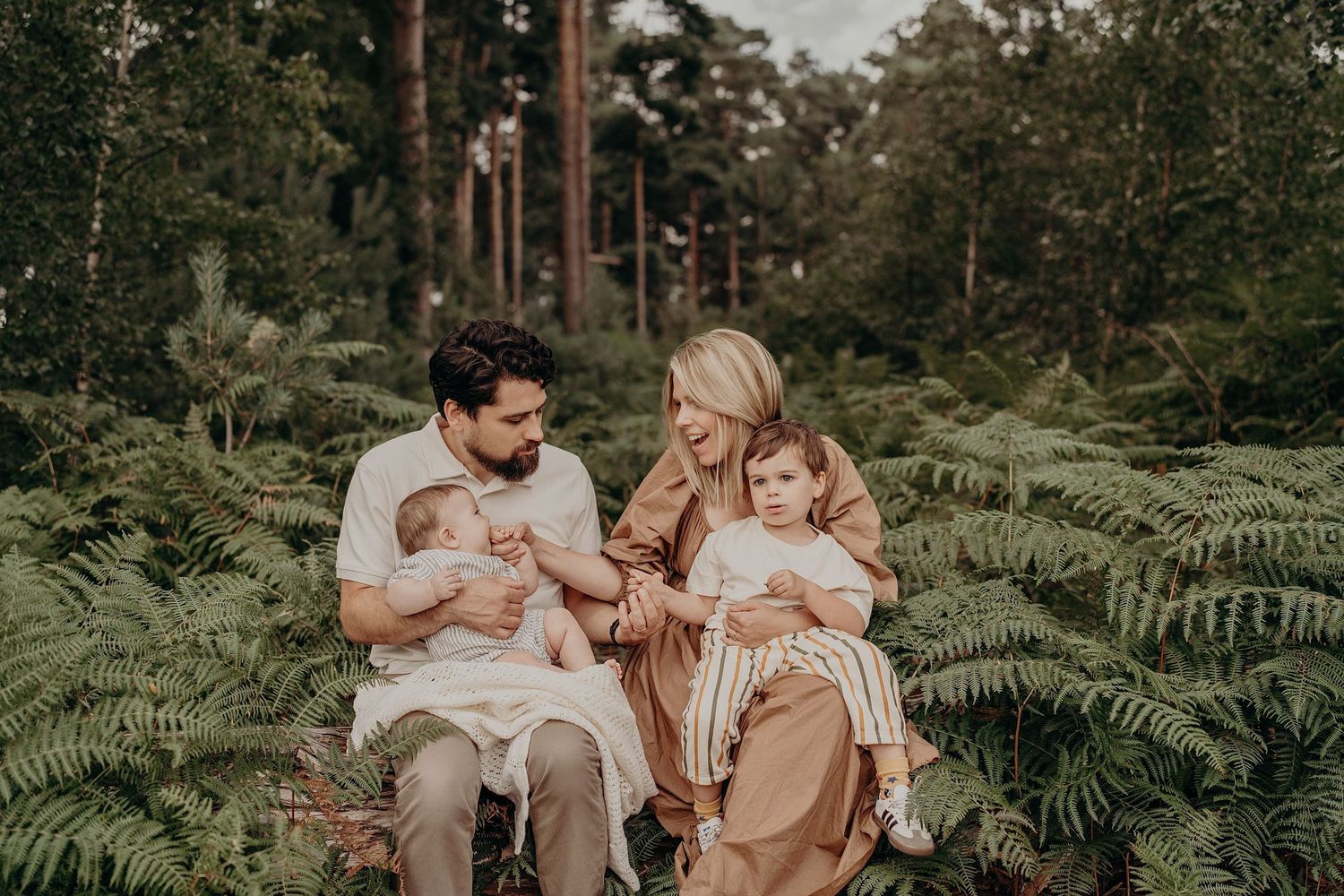 Lifestyle family photography in a lush green forest setting during golden hour.