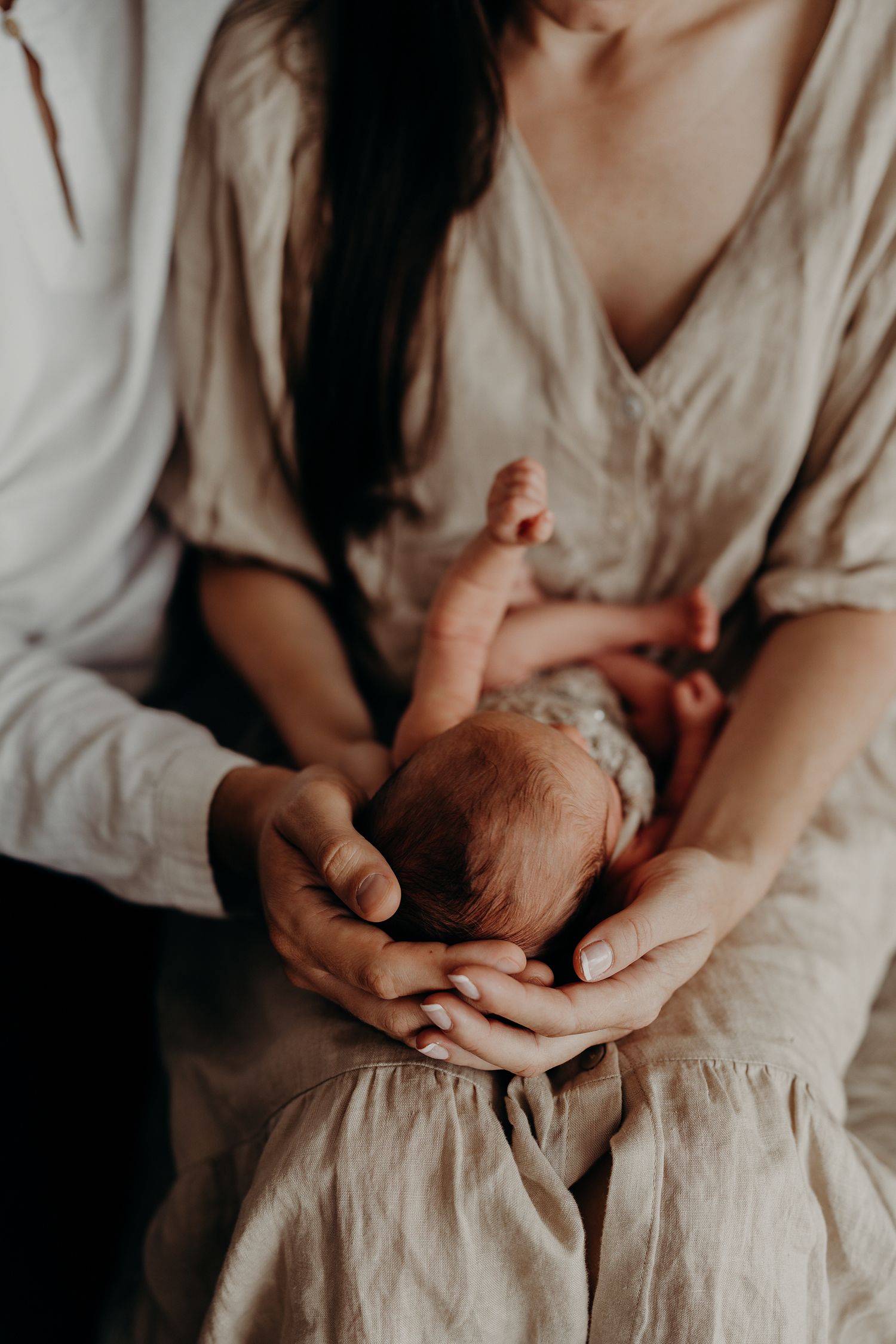 Gentle hands cradling a newborn baby in soft natural light.