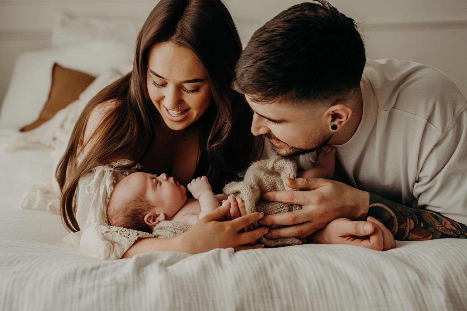 Newborn family lifestyle session in Dublin with parents cuddling their baby on white bedding