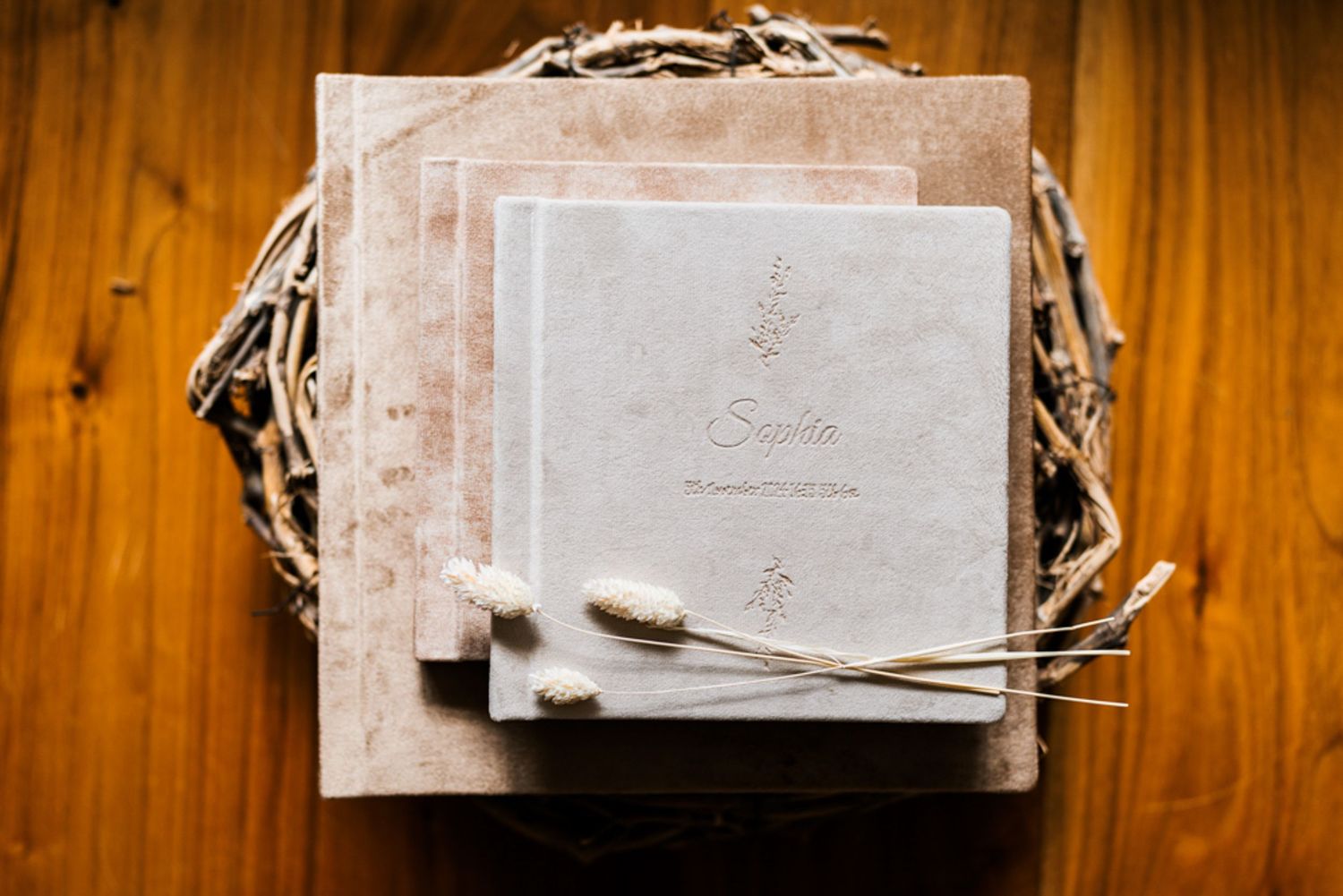 Stack of white photo albums or books arranged on wooden surface.
