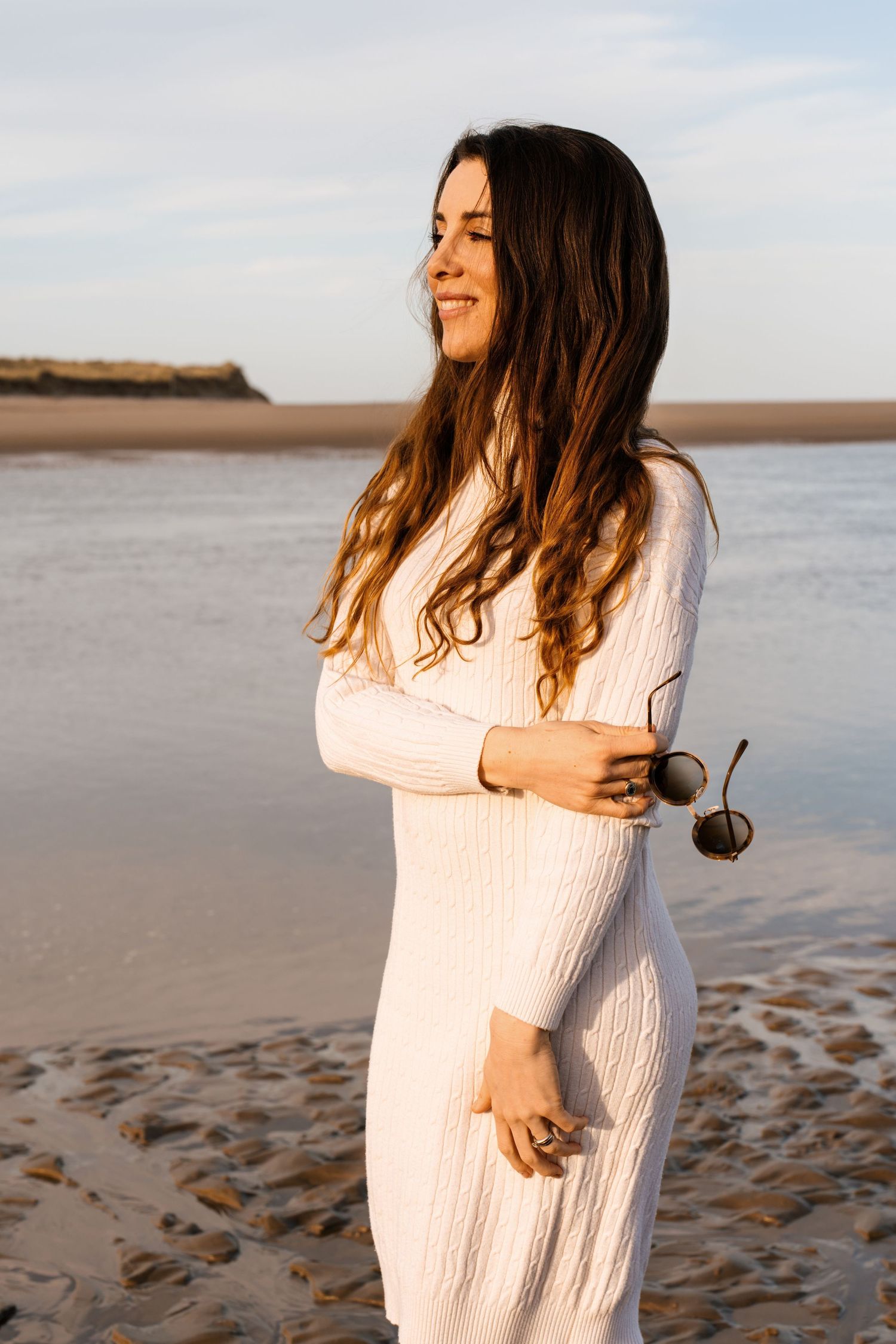 Beach photoshoot sequence featuring a white knit sweater against a coastal backdrop.