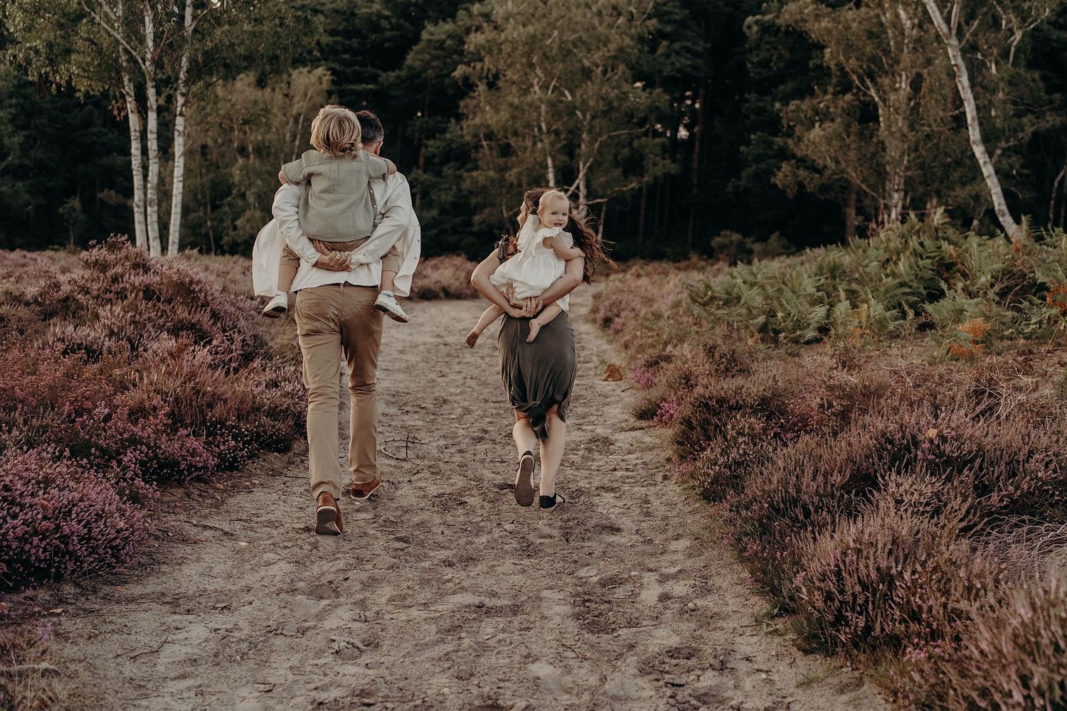 Family walking together through a scenic heather field at dusk.