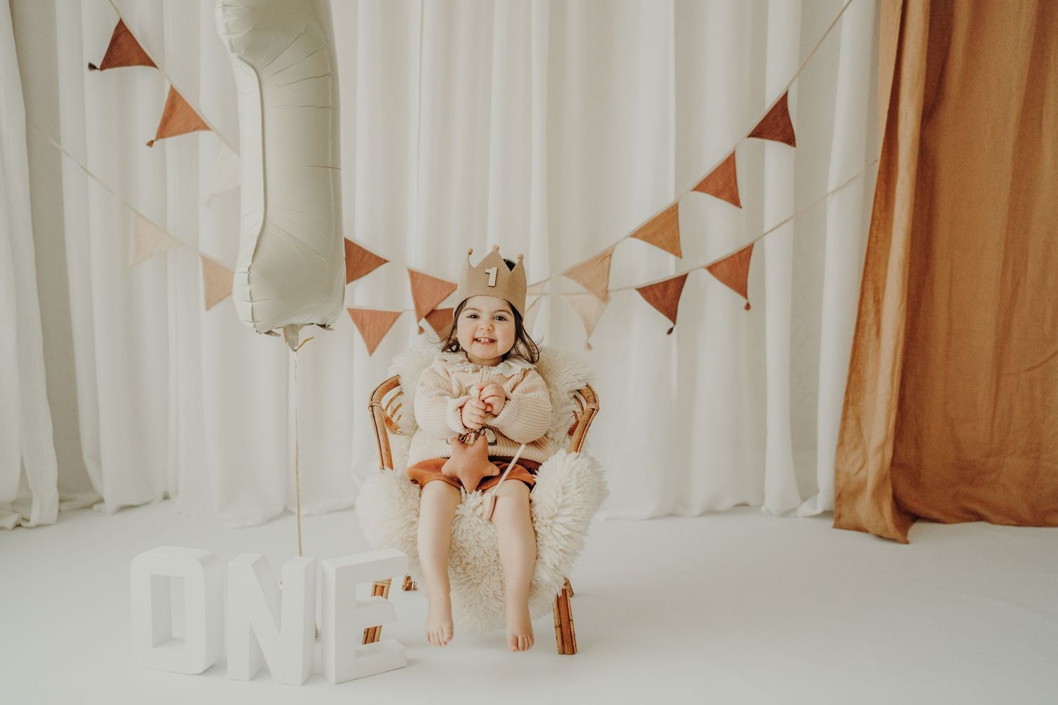 Decorative triangle bunting banners hanging against white curtains in a nursery setting.