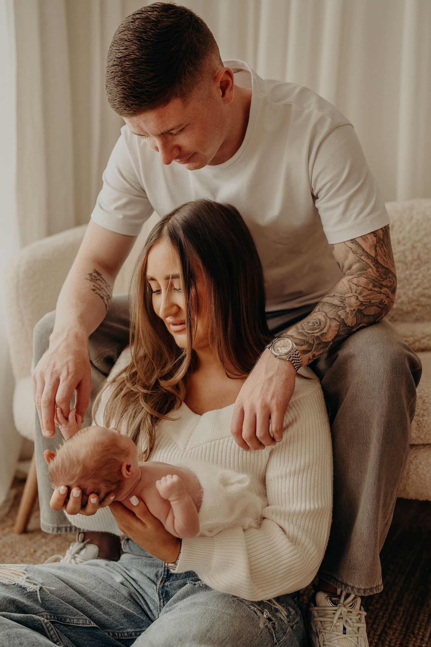 Family sharing intimate moment with newborn in cozy home setting.
