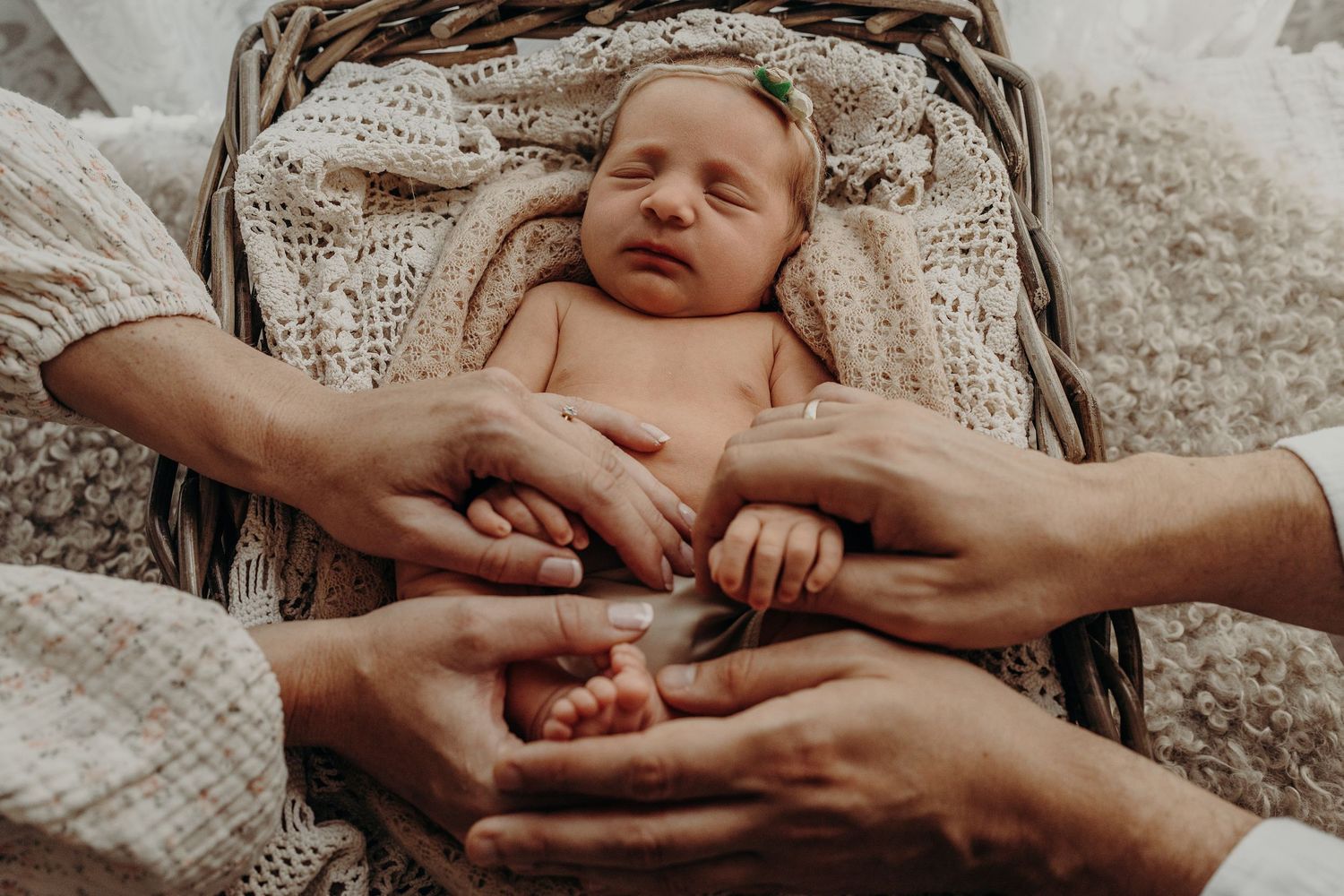 Baby rests peacefully in wicker chair during professional photography session.