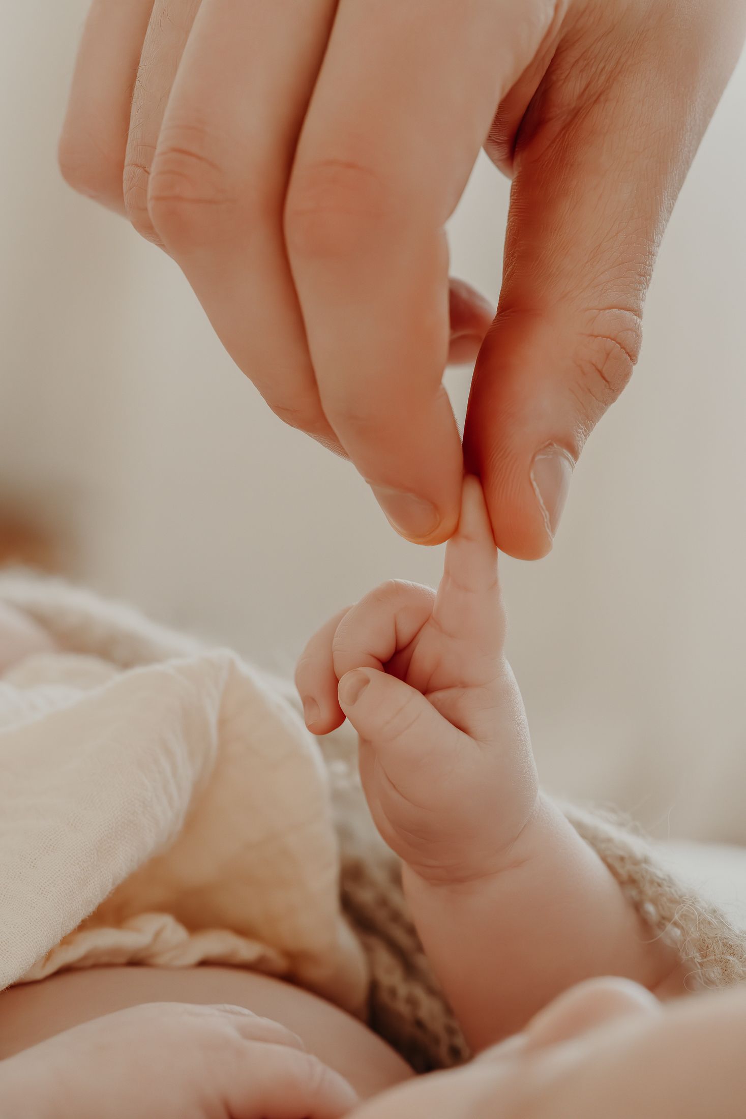 A close-up of hands gently holding babies finger, macro photography, natural newborn session Dublin
