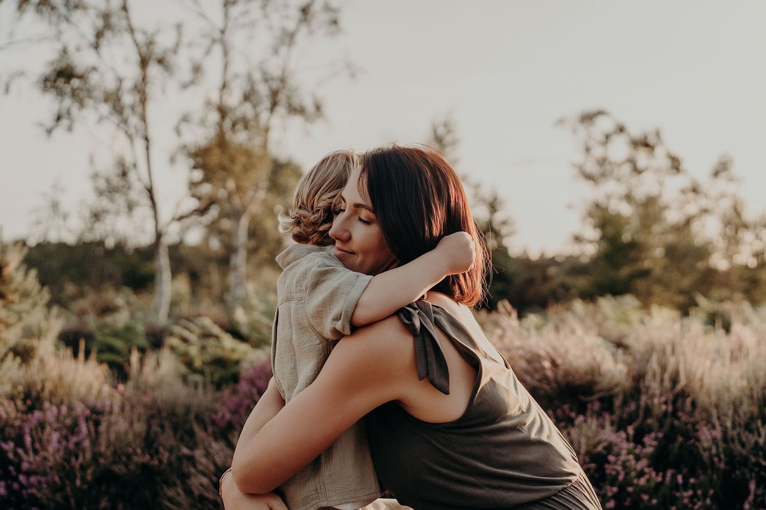Loving family embraces captured in a natural outdoor setting at sunset.