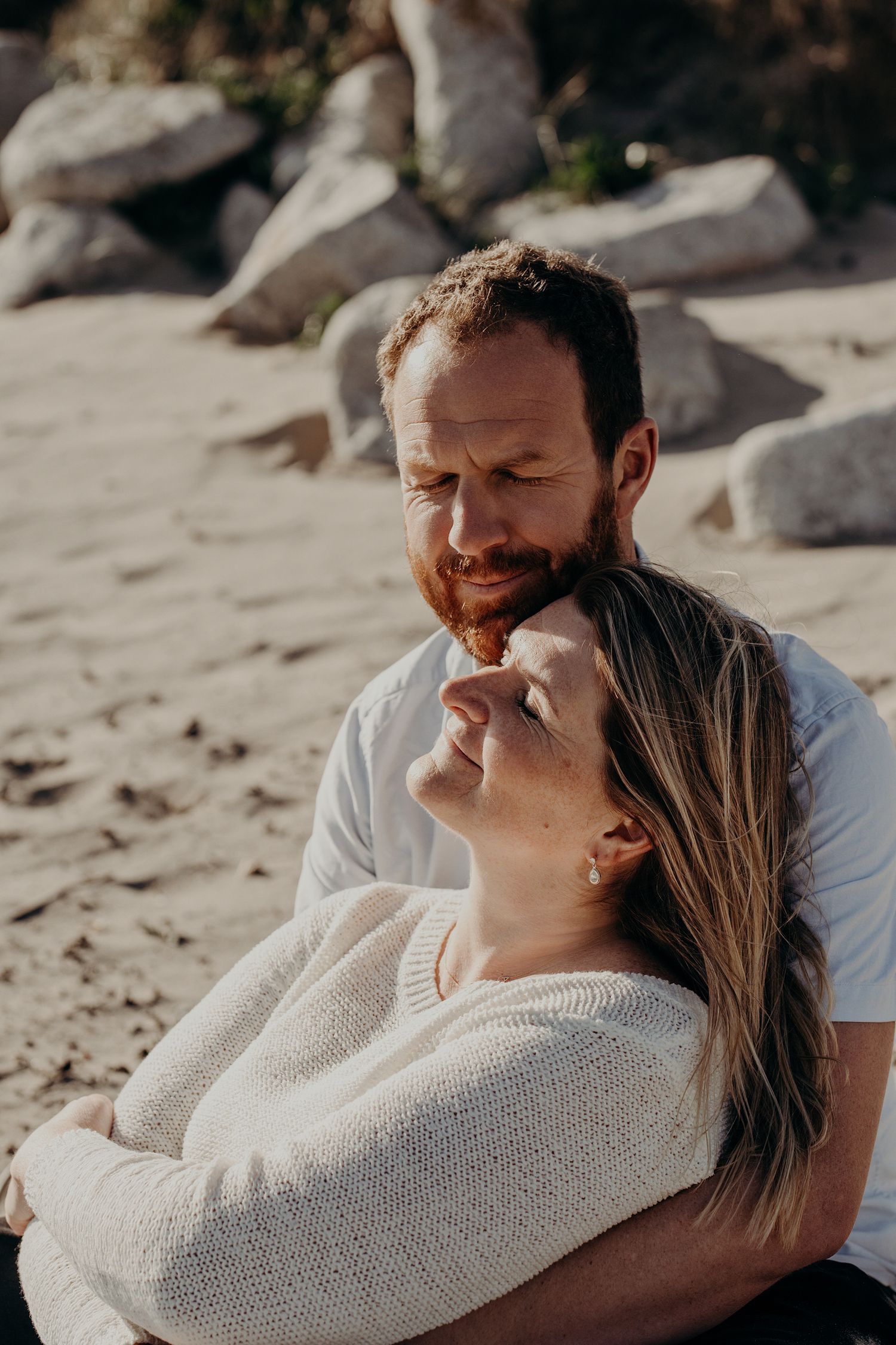 Couple sharing intimate moment on sandy beach.