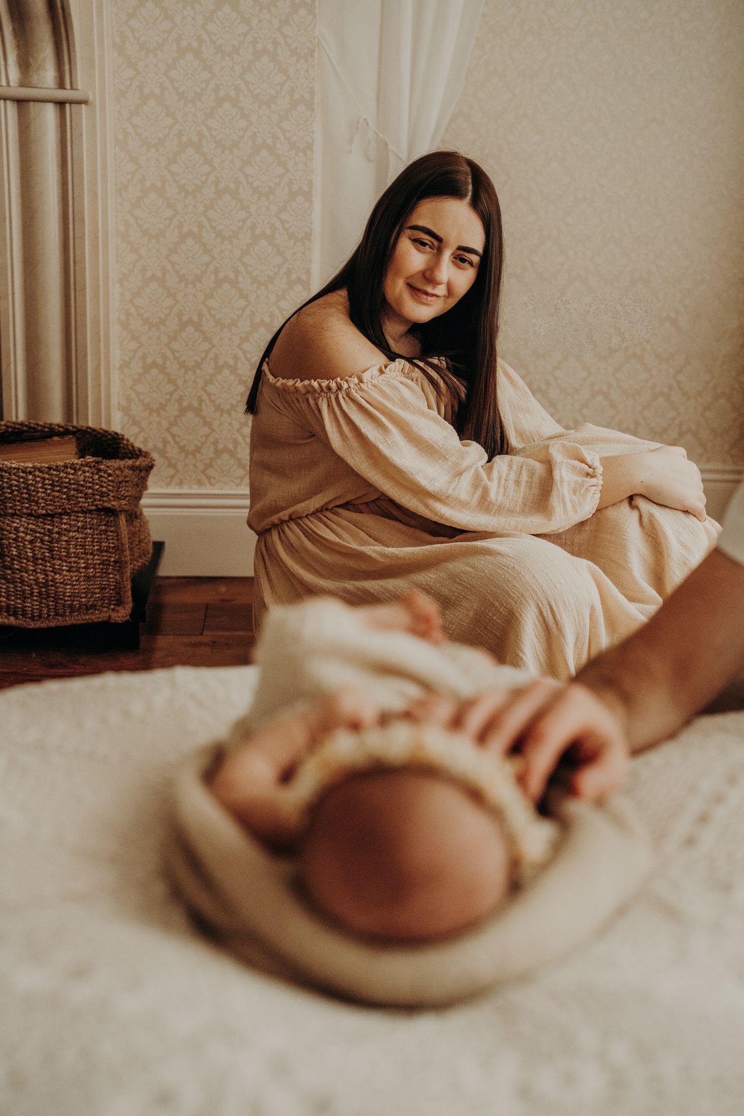 Soft natural light photo of someone resting on a bed with textured wallpaper background.