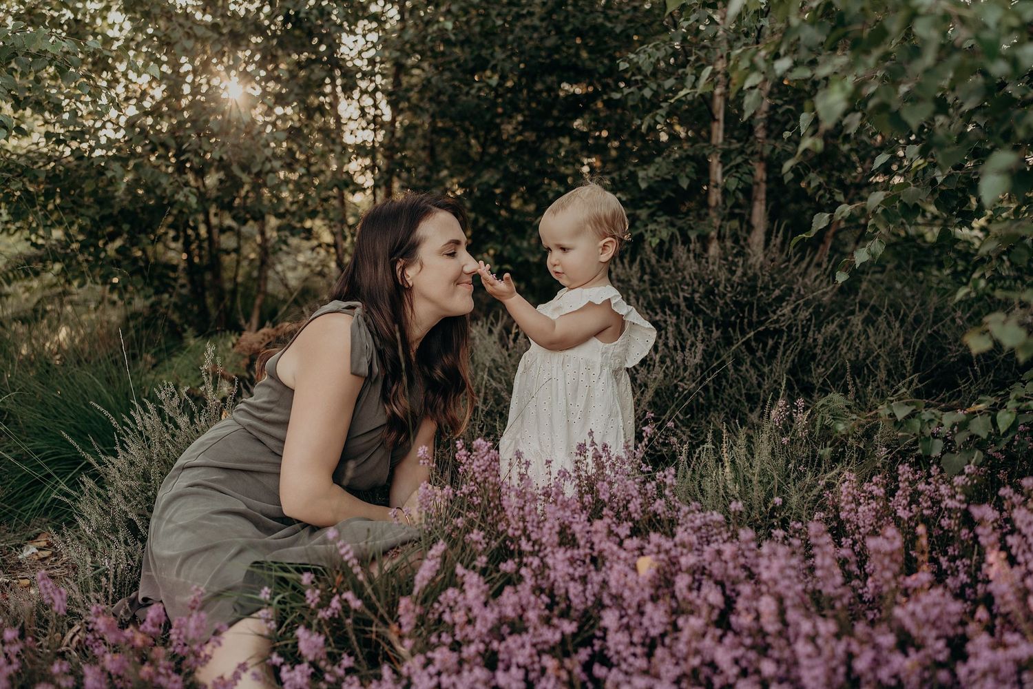 Family portrait session among purple wildflowers during golden hour.