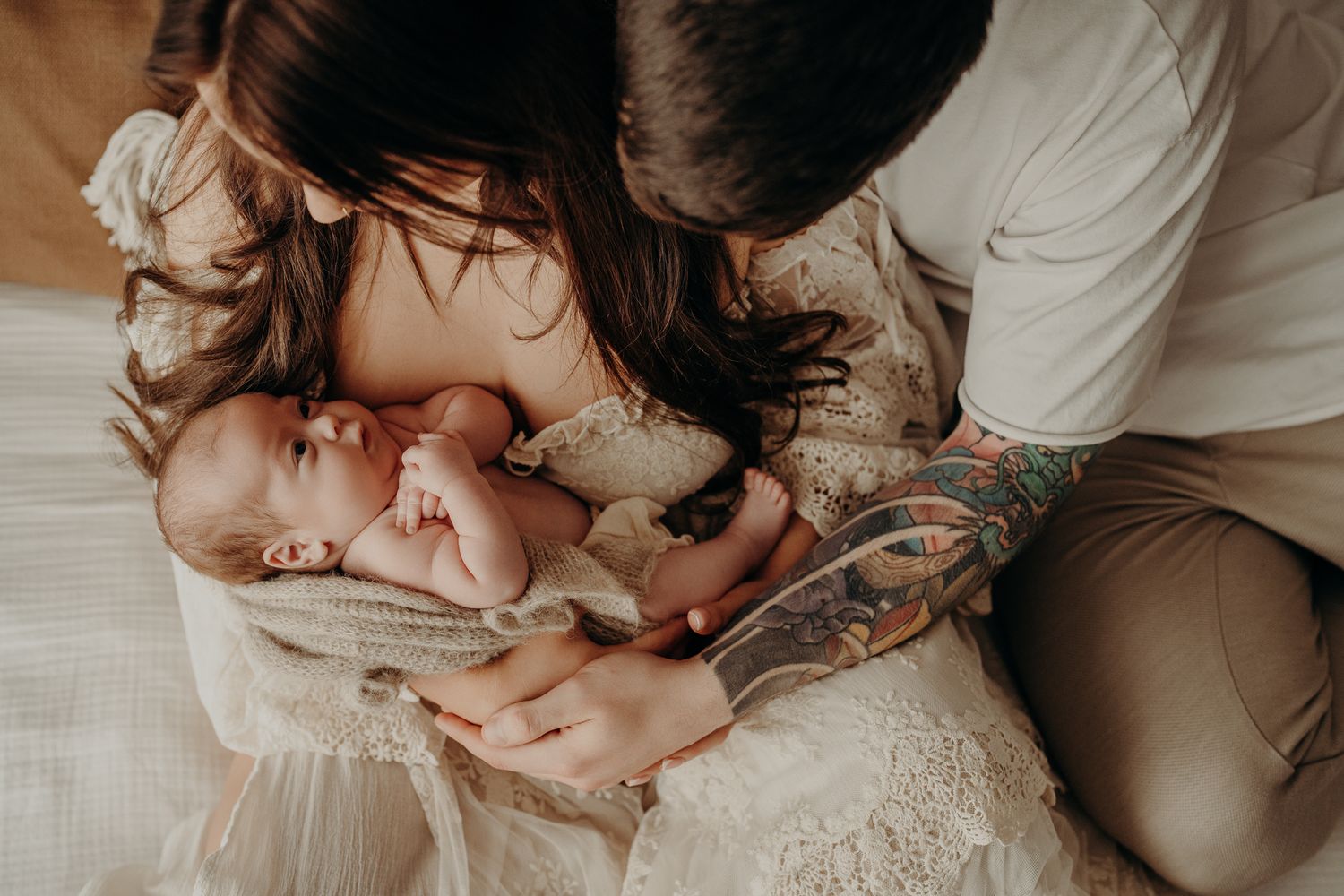 Parents hugging their newborn on white bedding during a natural lifestyle newborn session in Dublin studio